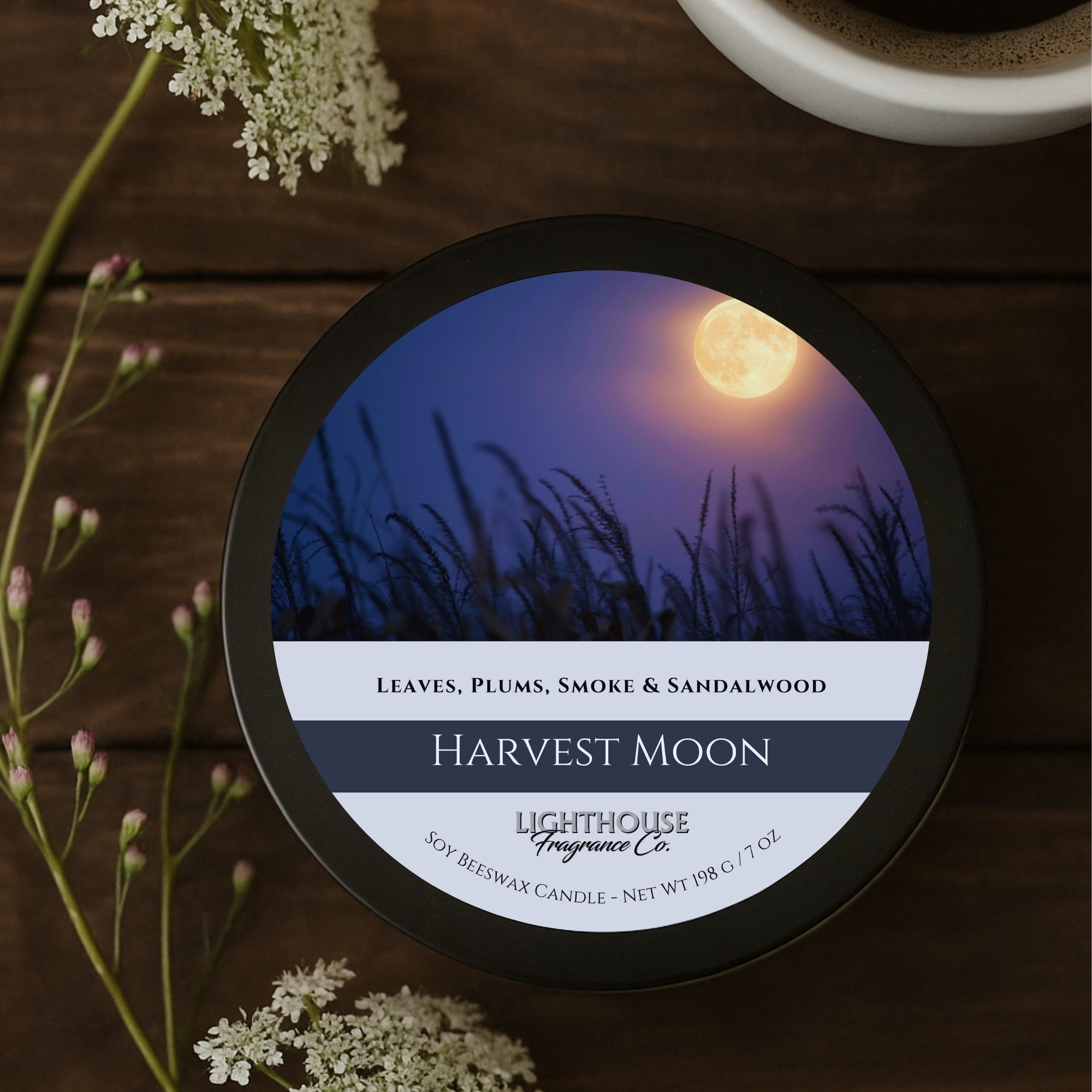 Candle with 'Harvest Moon' label on a wooden surface with flowers