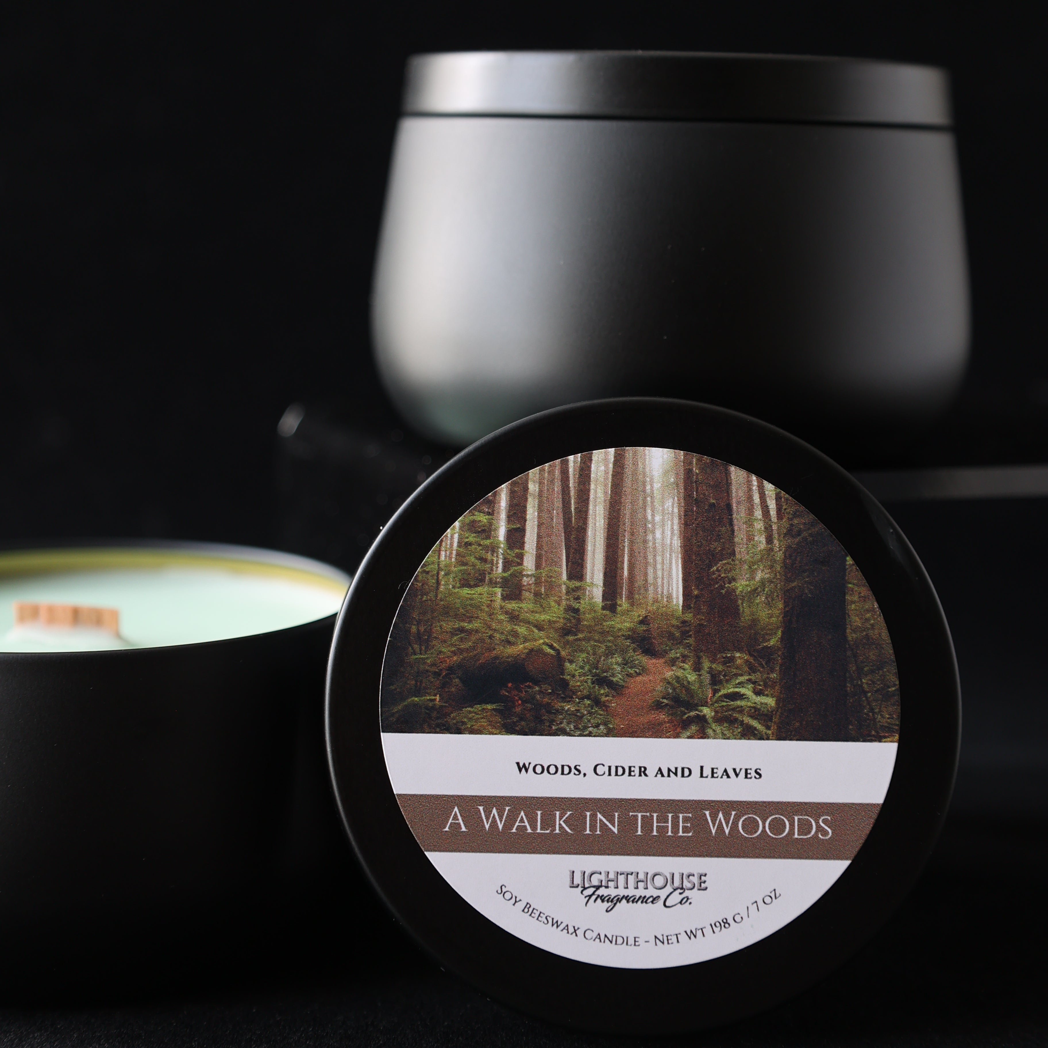 Black tin candle with a label featuring a nature scene on a dark background