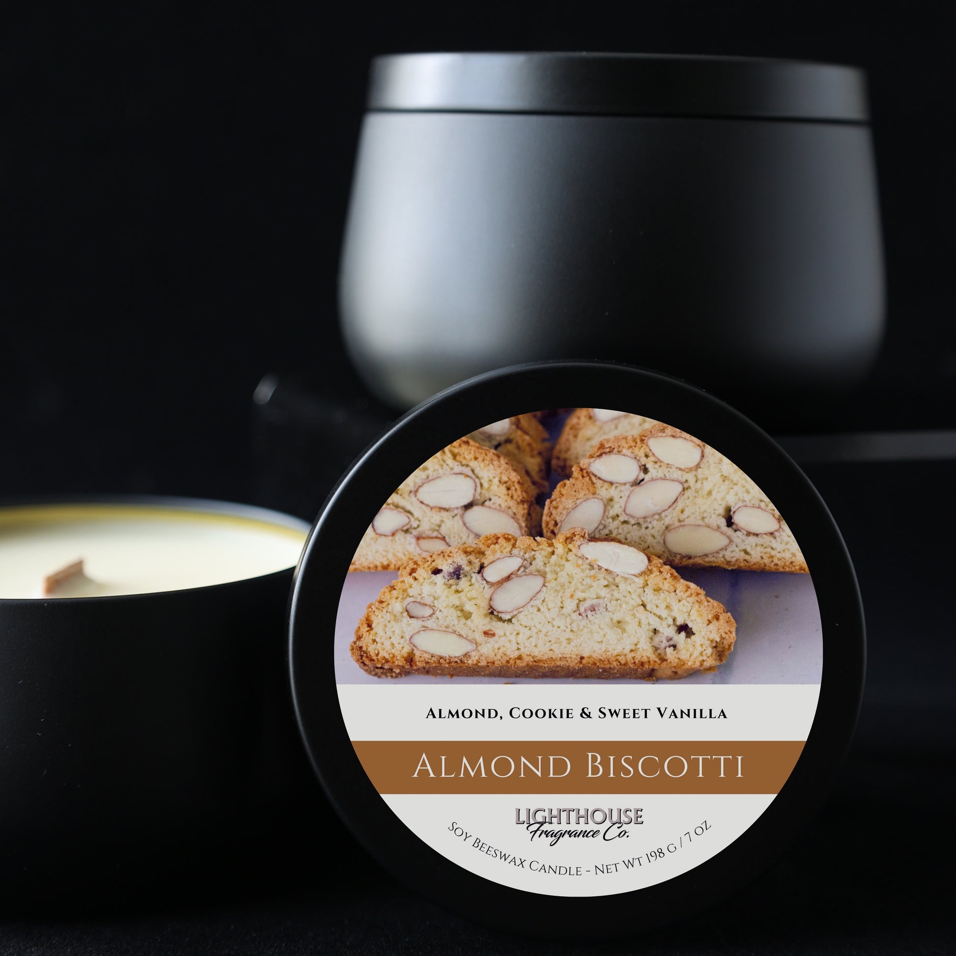 Black candle with a label featuring almond biscotti on a dark background