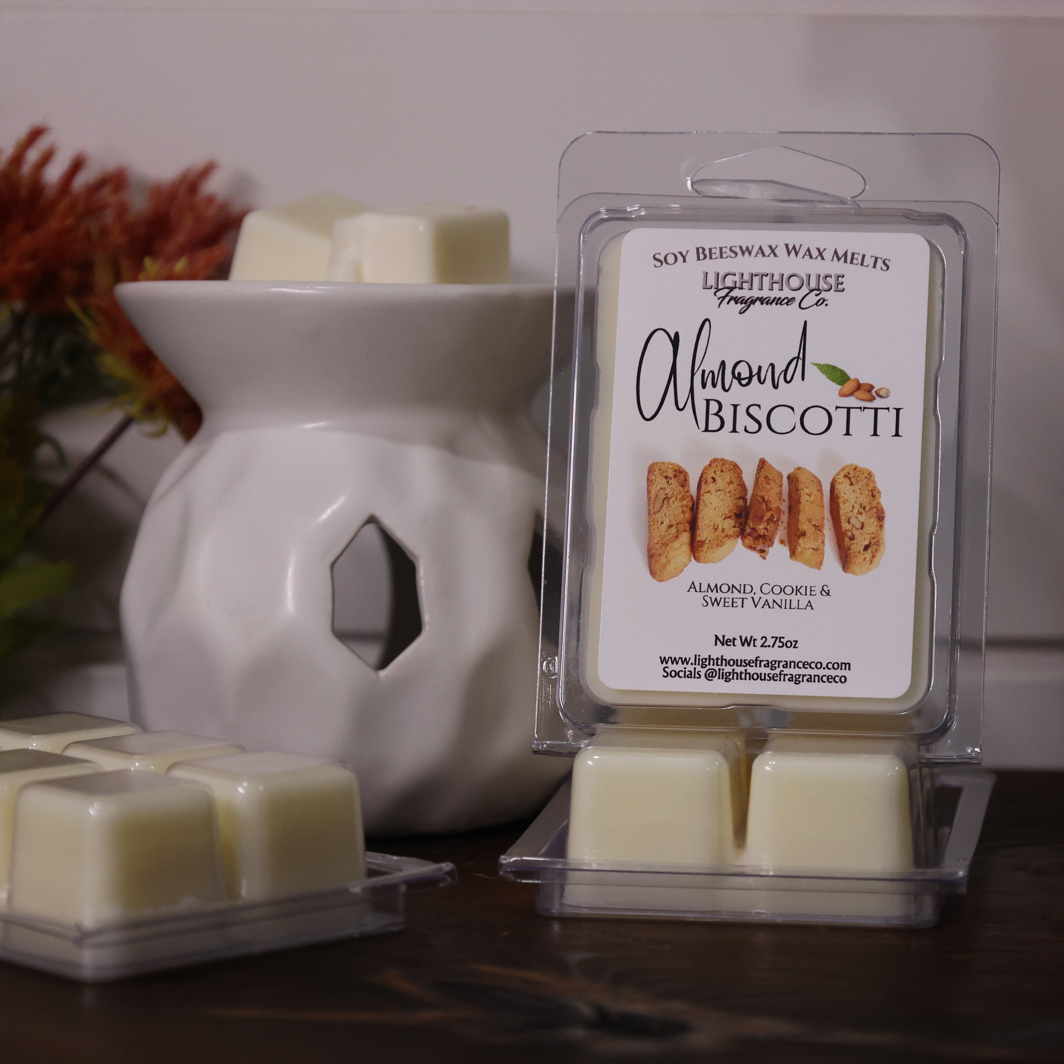 Almond Biscotti wax melts in packaging with a white wax warmer on a wooden surface.