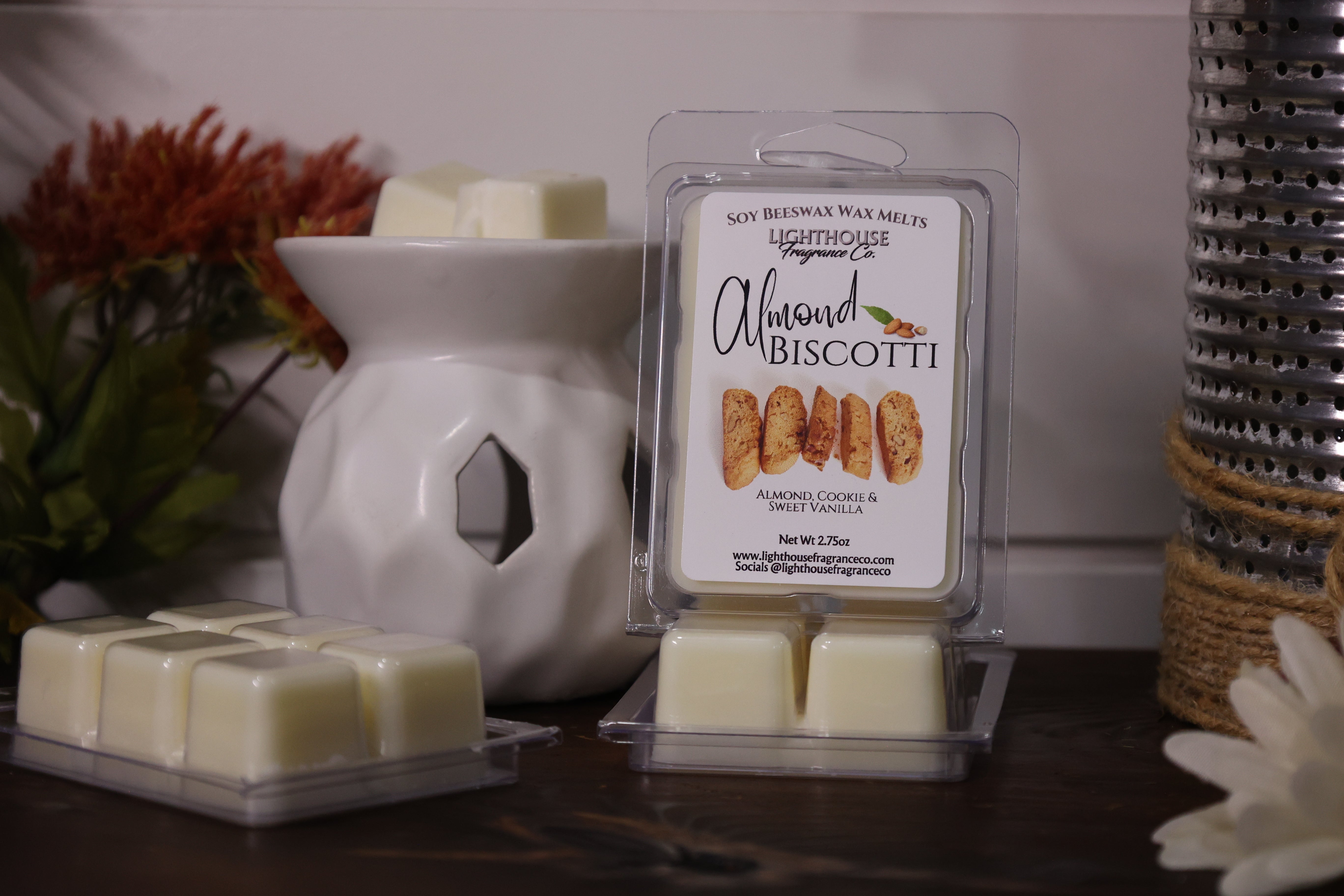 Almond Biscotti wax melts in packaging with a white wax warmer on a wooden surface.
