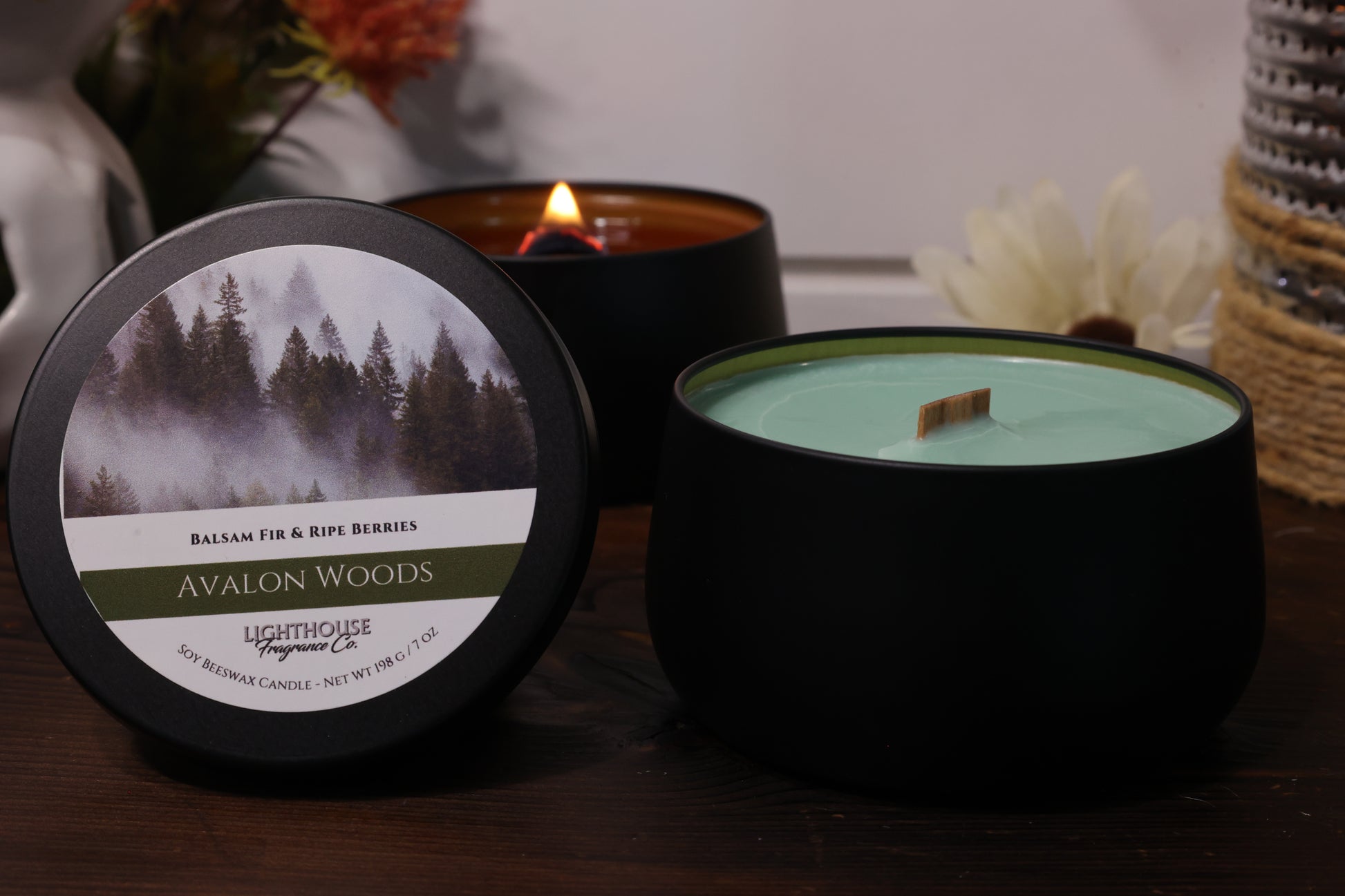 Avalon Woods candle with a label featuring a forest design on a wooden surface.