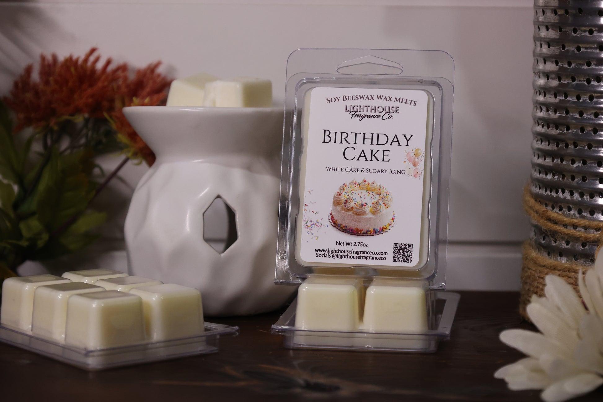 Packaged 'Birthday Cake' wax melts with a wax warmer and decorative items on a surface.