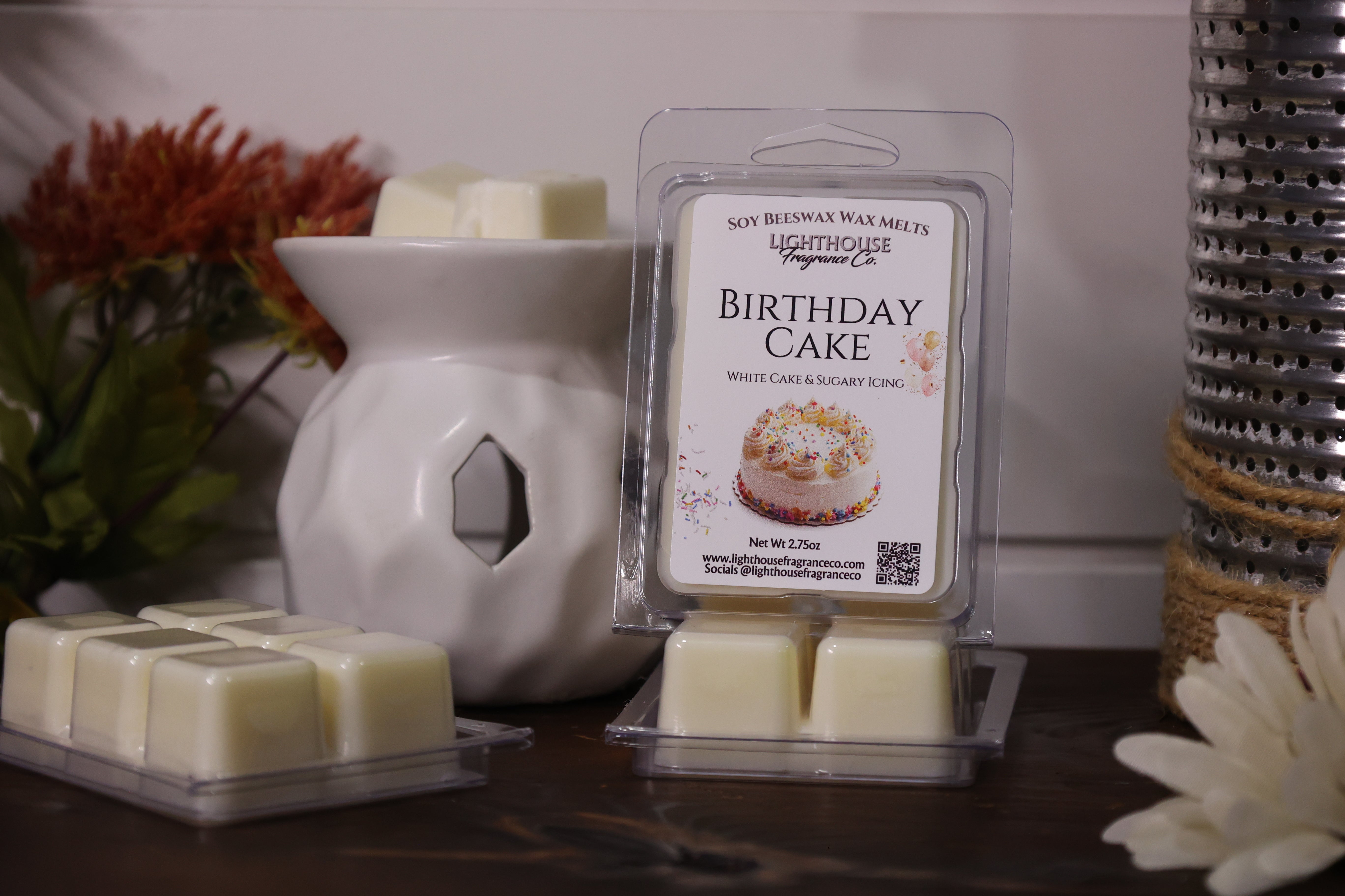 Packaged 'Birthday Cake' wax melts with a wax warmer and decorative items on a surface.