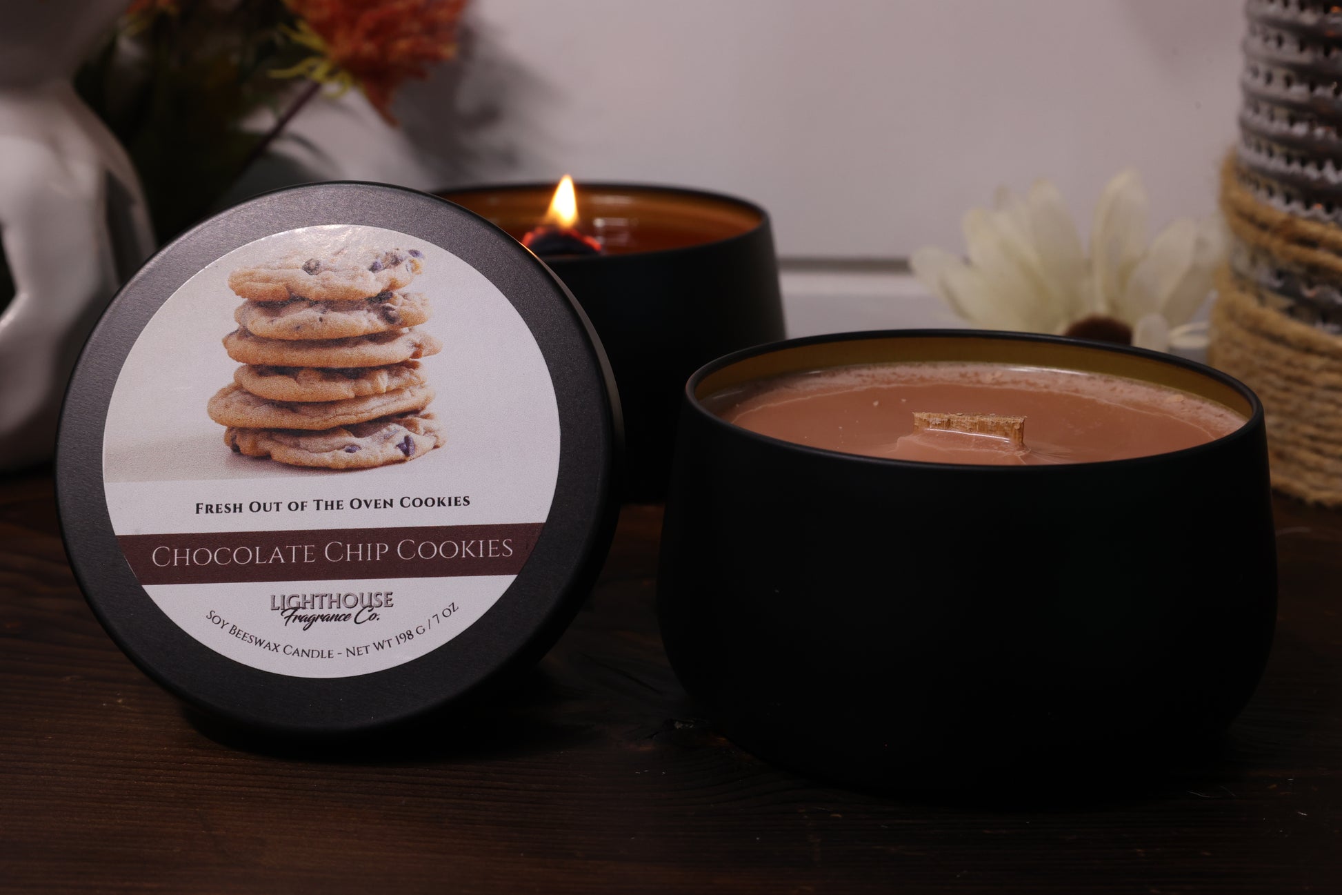 Black candle with a label featuring cookies and a lit candle in the background.