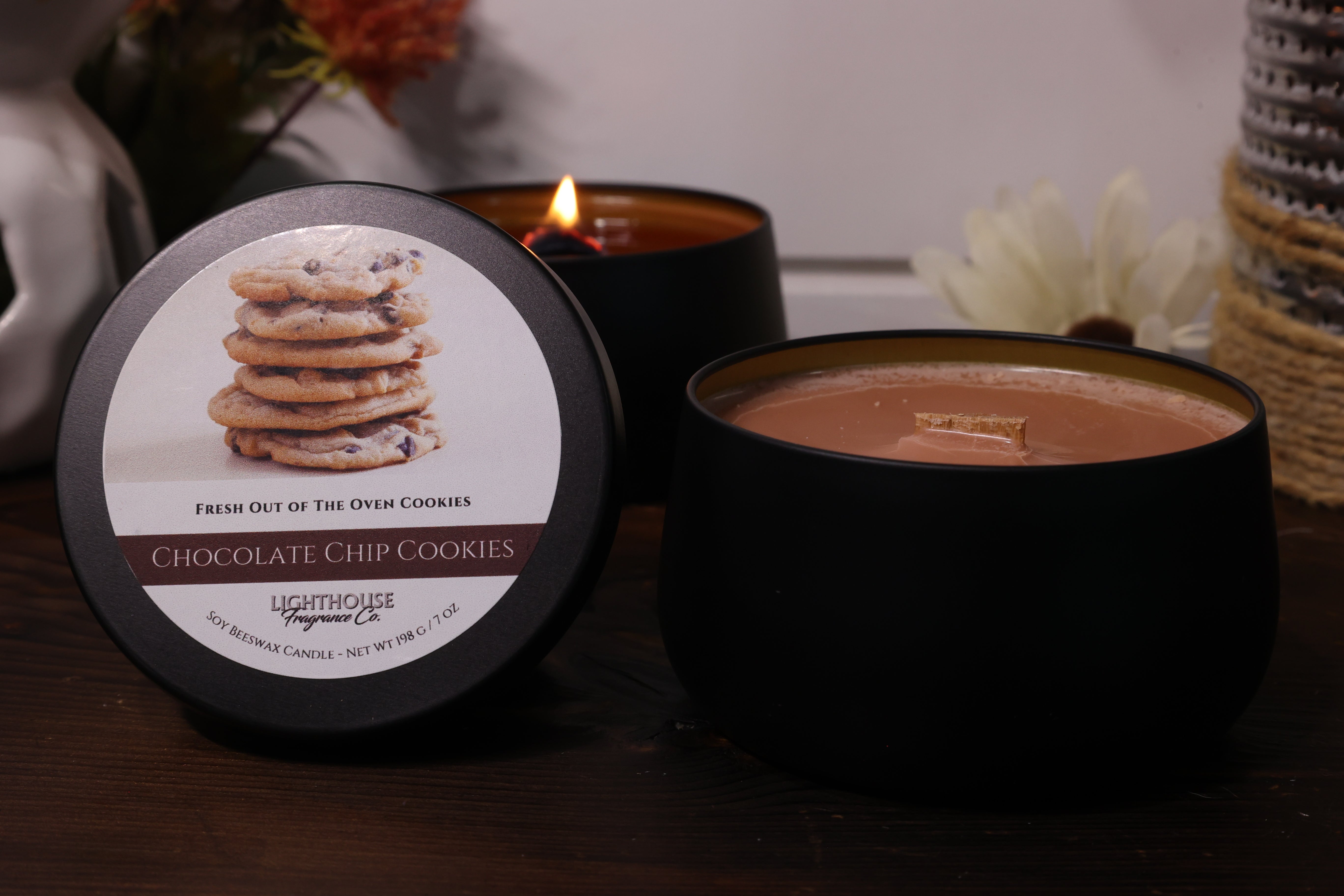 Black candle with a label featuring cookies and a lit candle in the background.