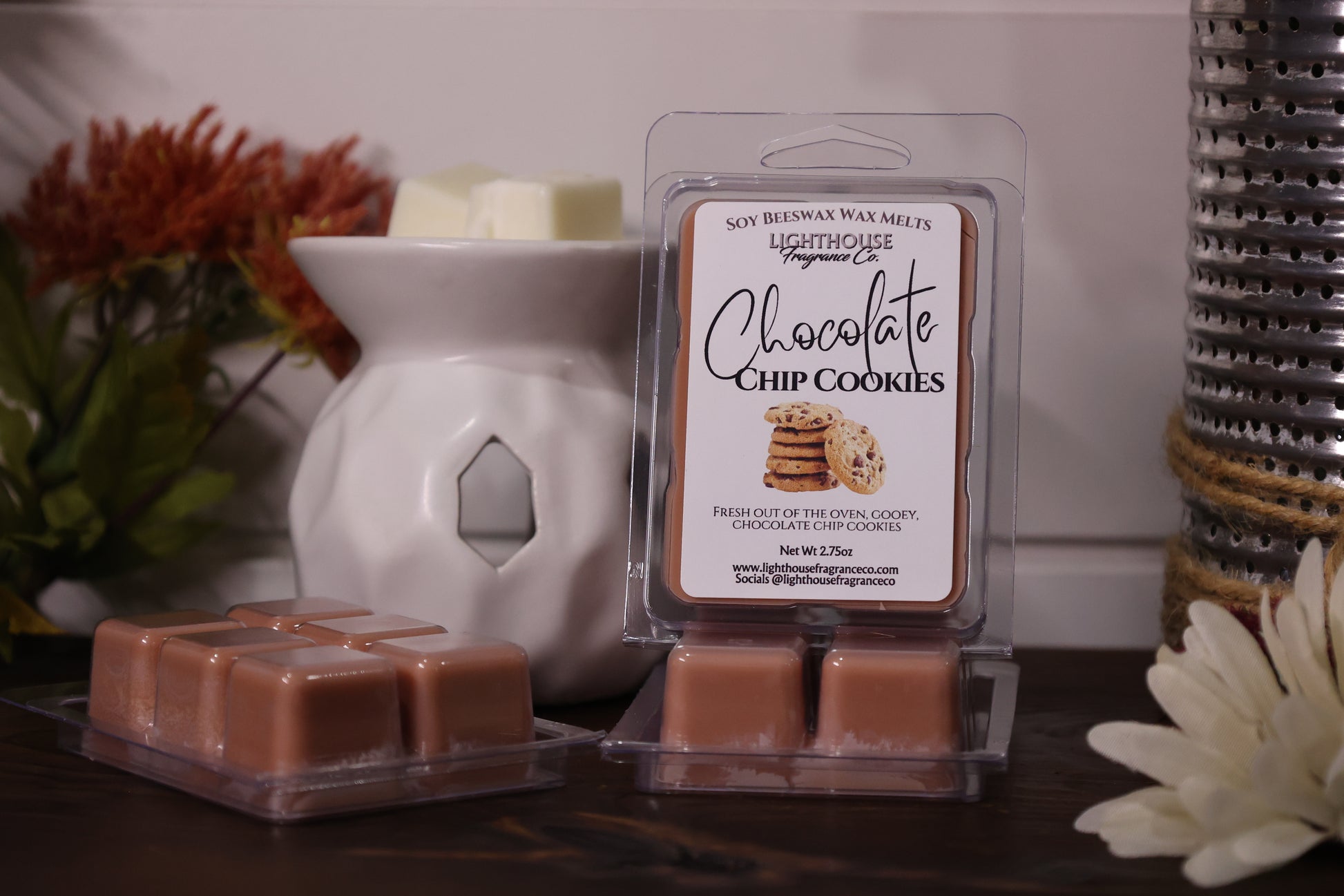 Packaged wax melts labeled 'Chocolate Chip Cookies' with a white wax warmer and decorative items.