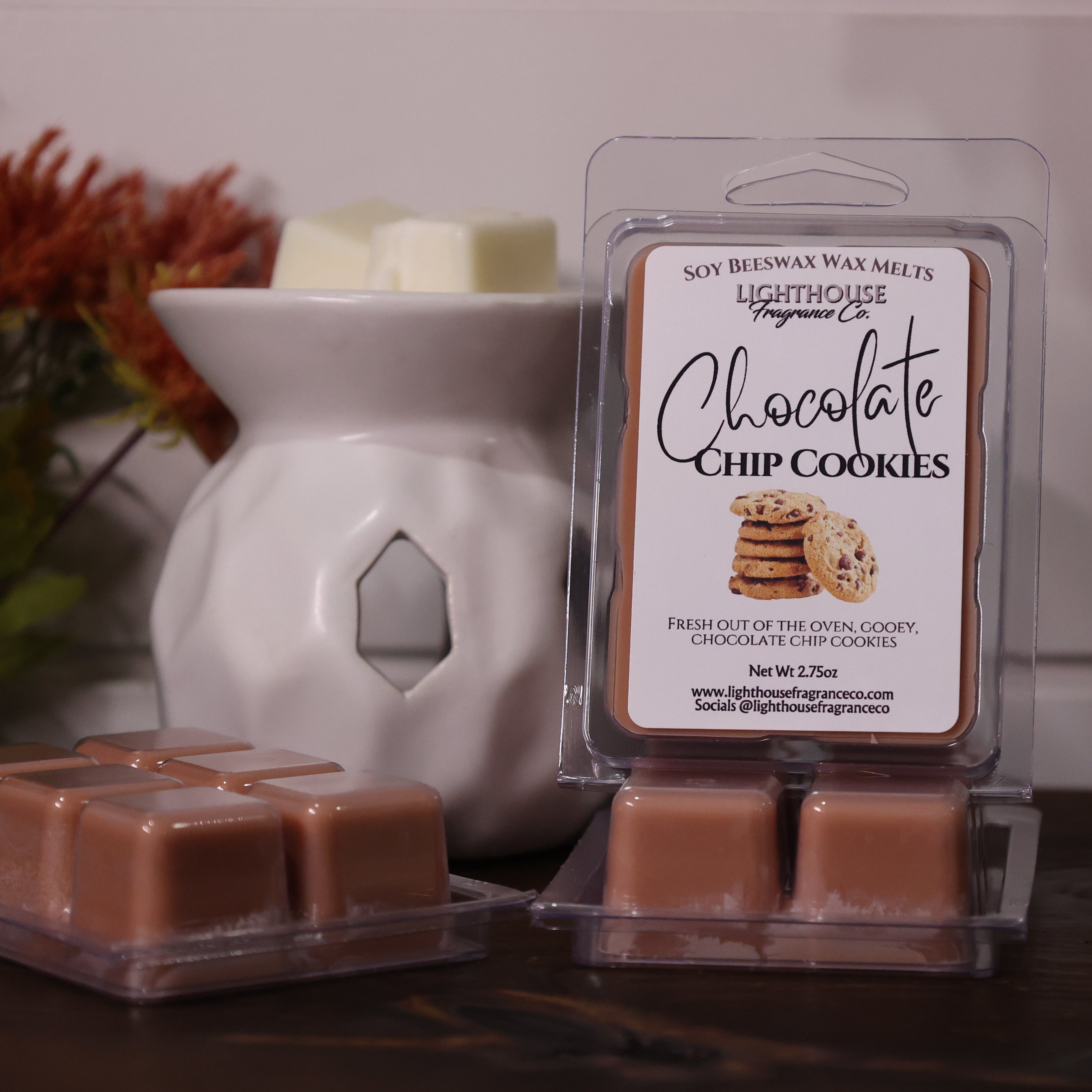 Packaged wax melts labeled 'Chocolate Chip Cookies' with a white wax warmer and decorative items.