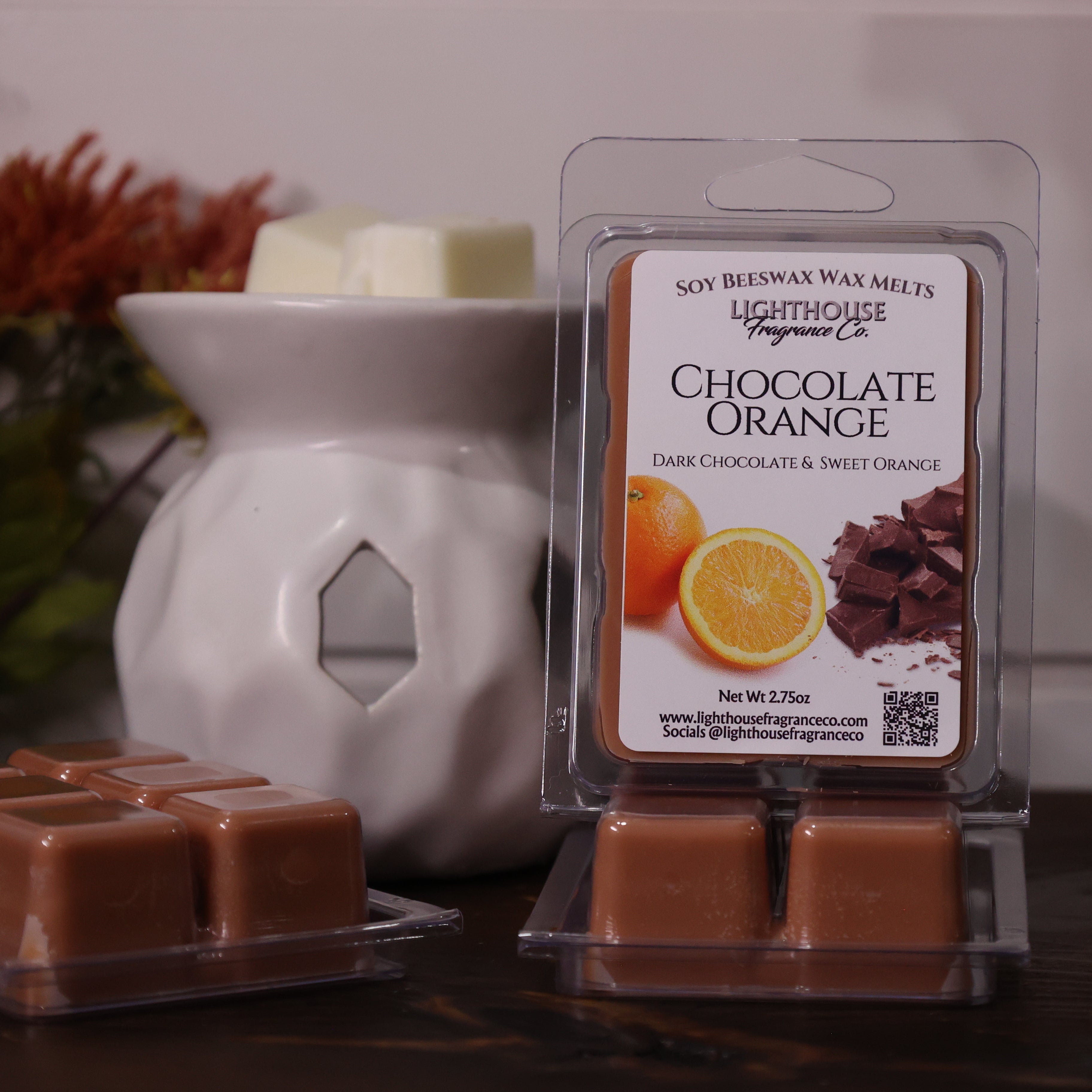 Chocolate orange wax melts in packaging with a wax warmer on a decorative surface.
