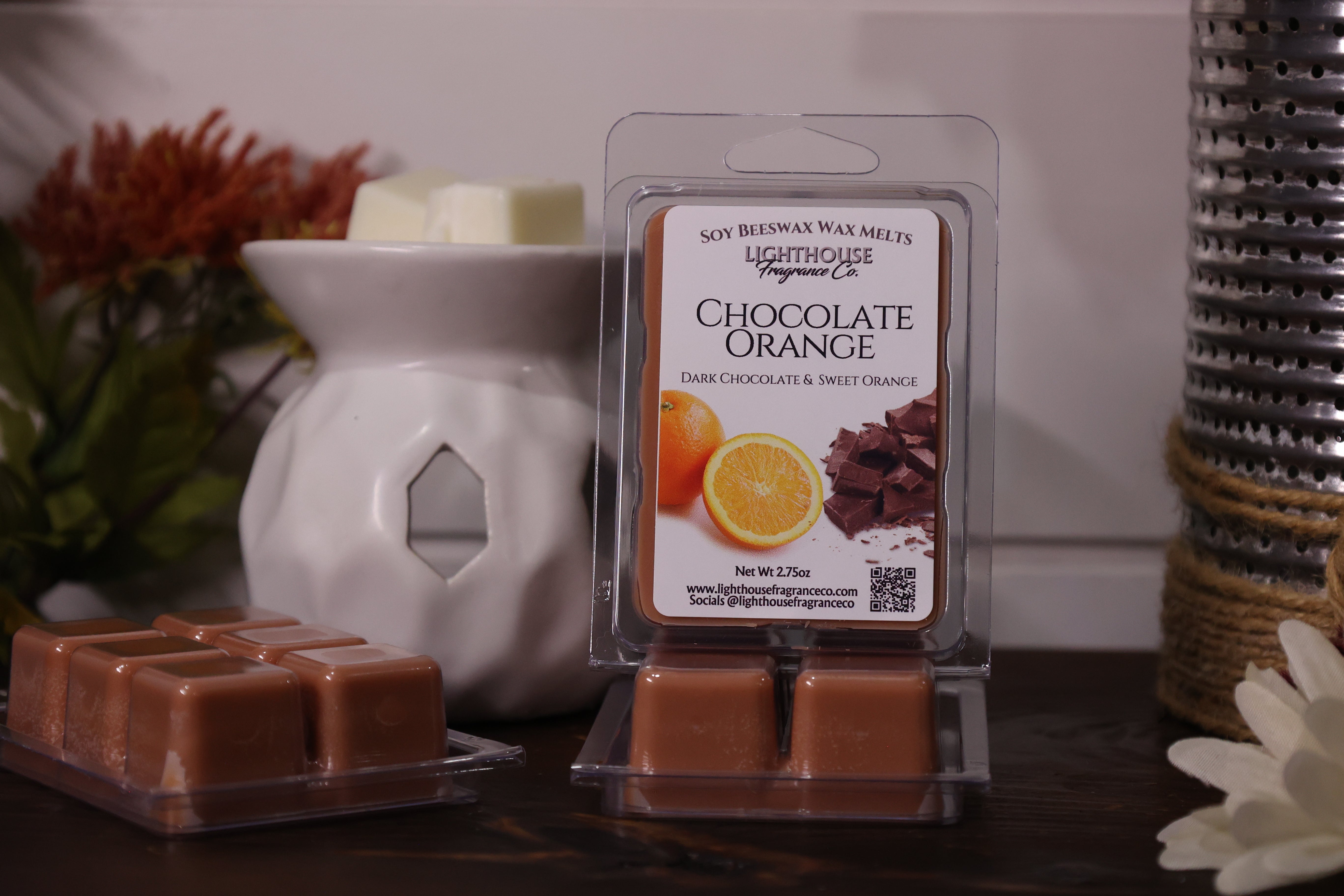 Chocolate orange wax melts in packaging with a wax warmer on a decorative surface.