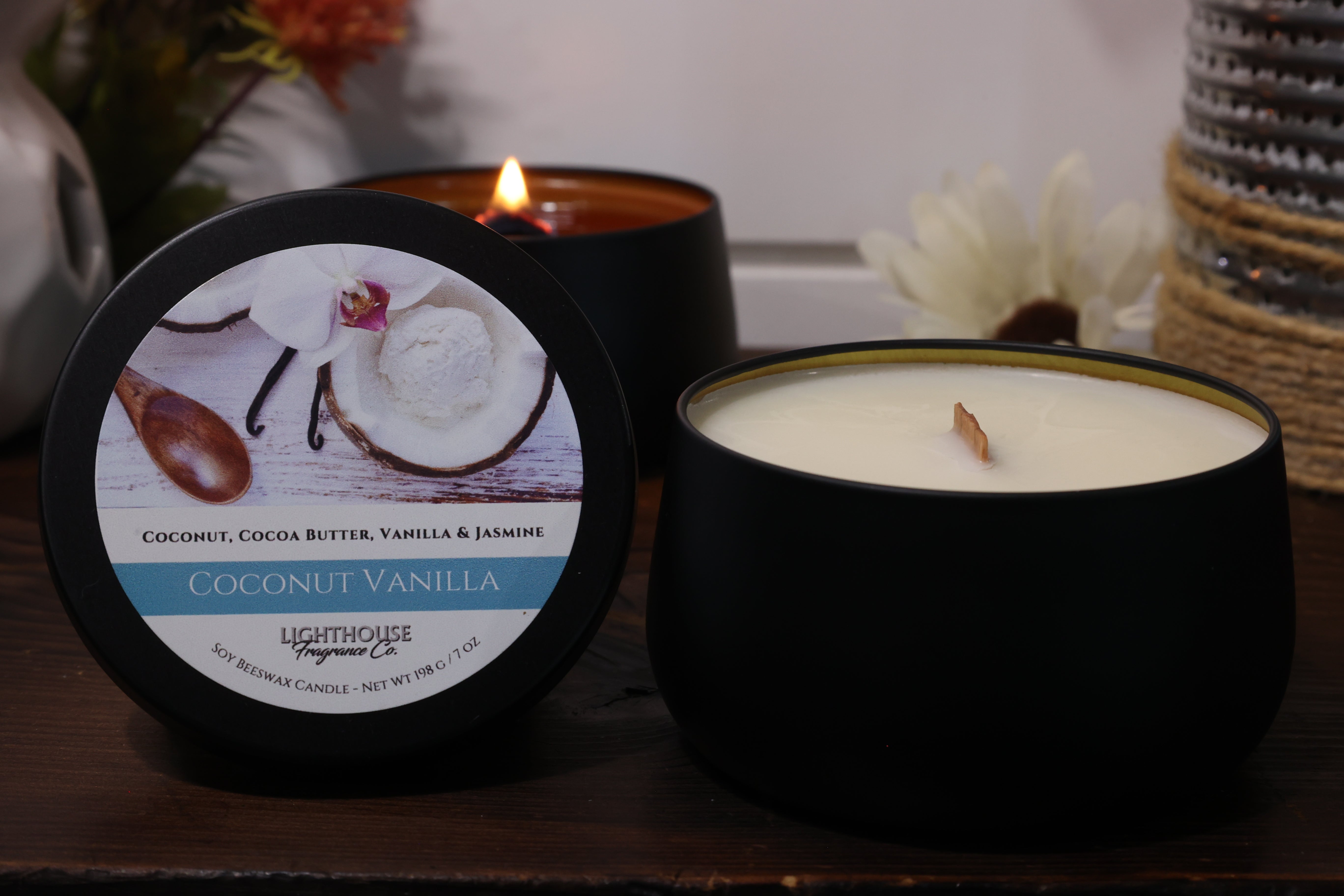 Two candles, one lit and one unlit, with a label on a wooden surface.