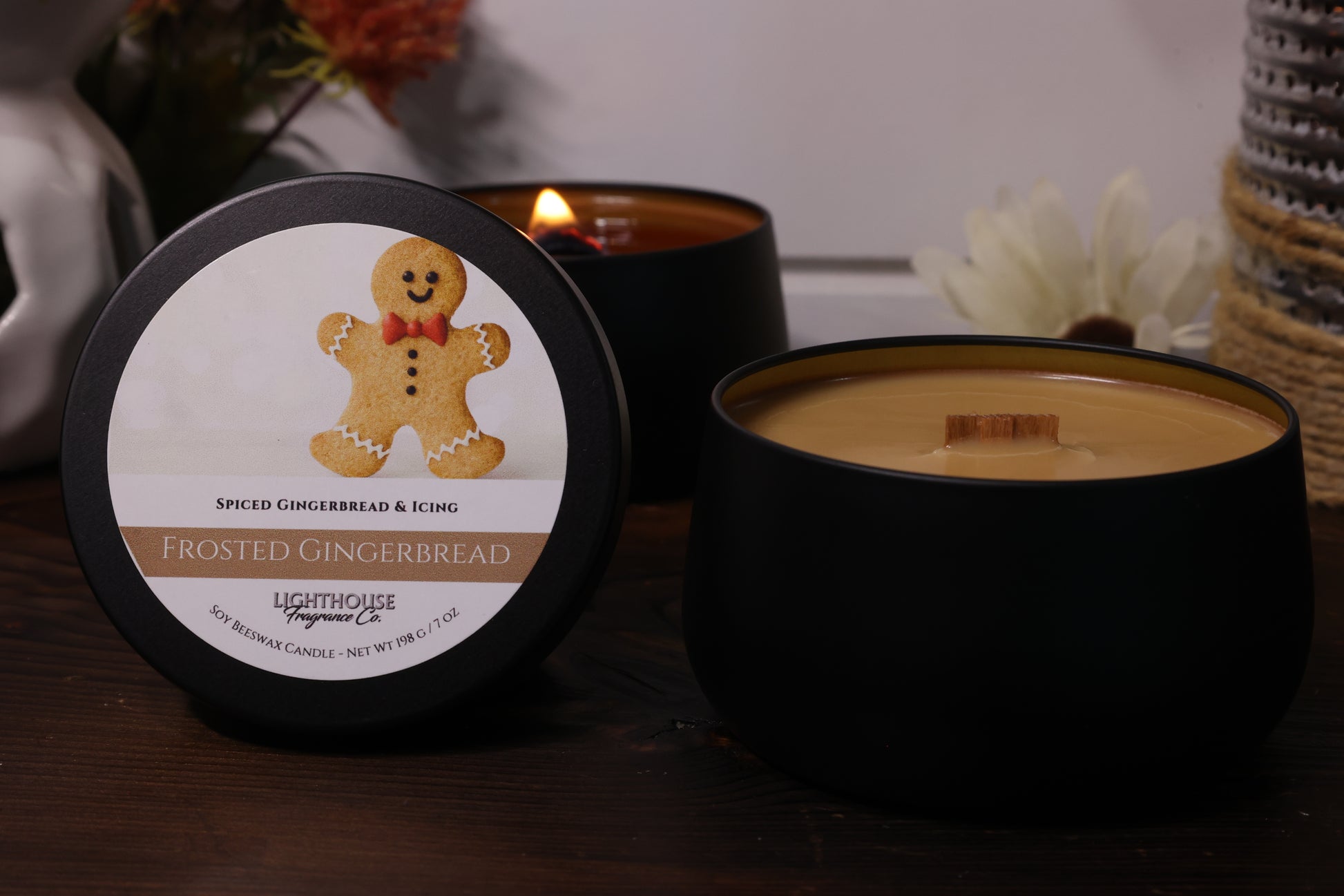 Black candle with a gingerbread man label on a wooden surface.