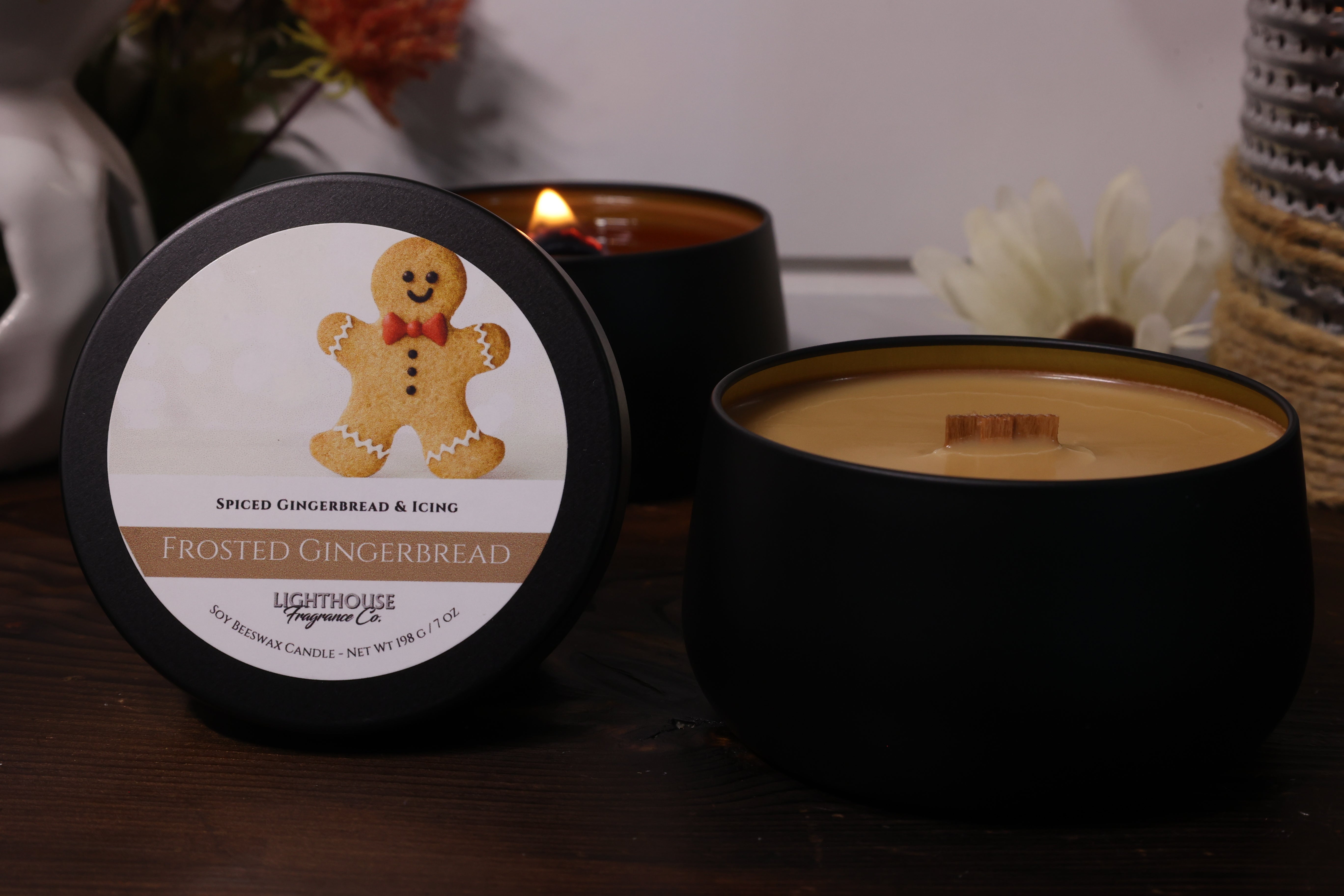 Black candle with a gingerbread man label on a wooden surface.