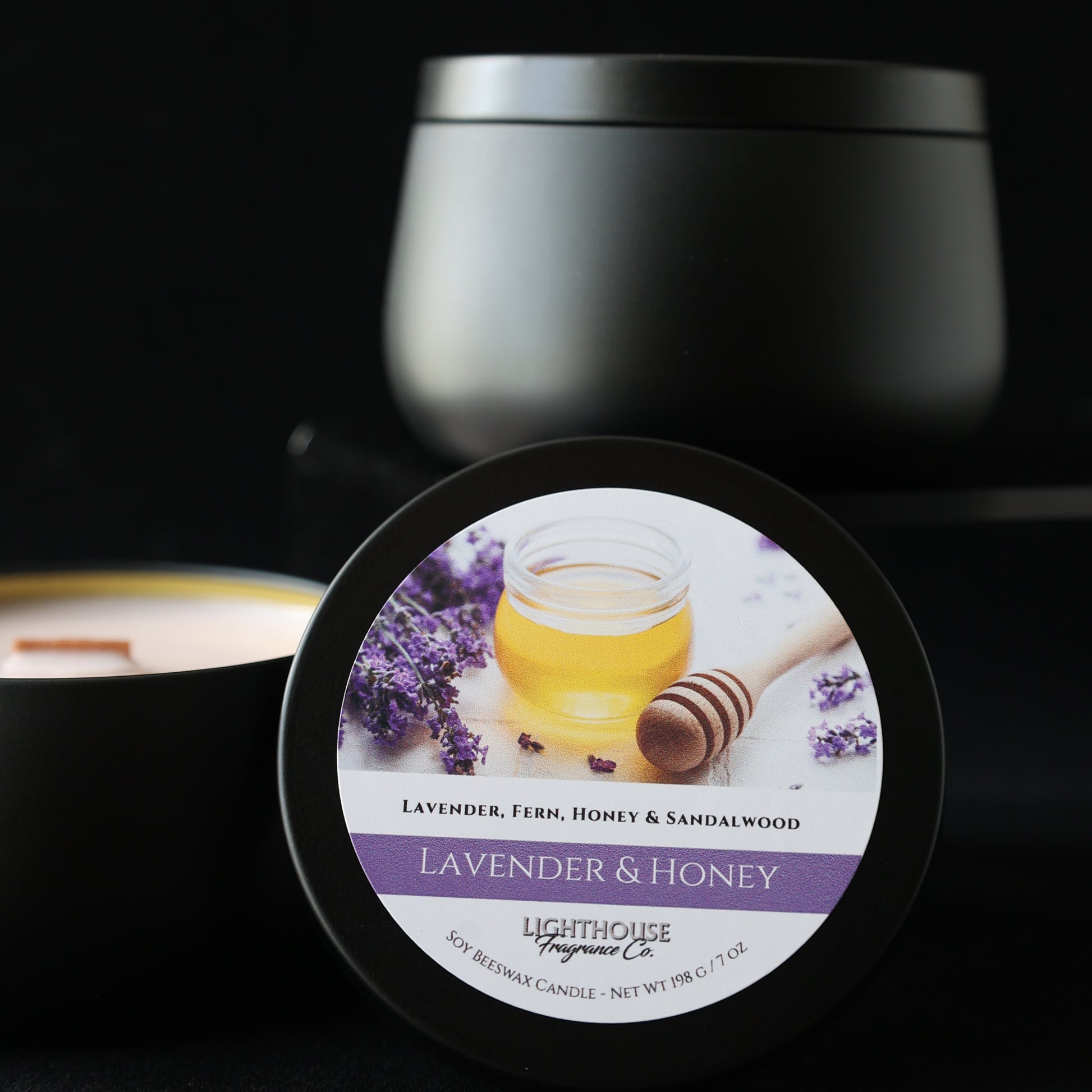 Jar of lavender and honey candle with a black lid on a dark background