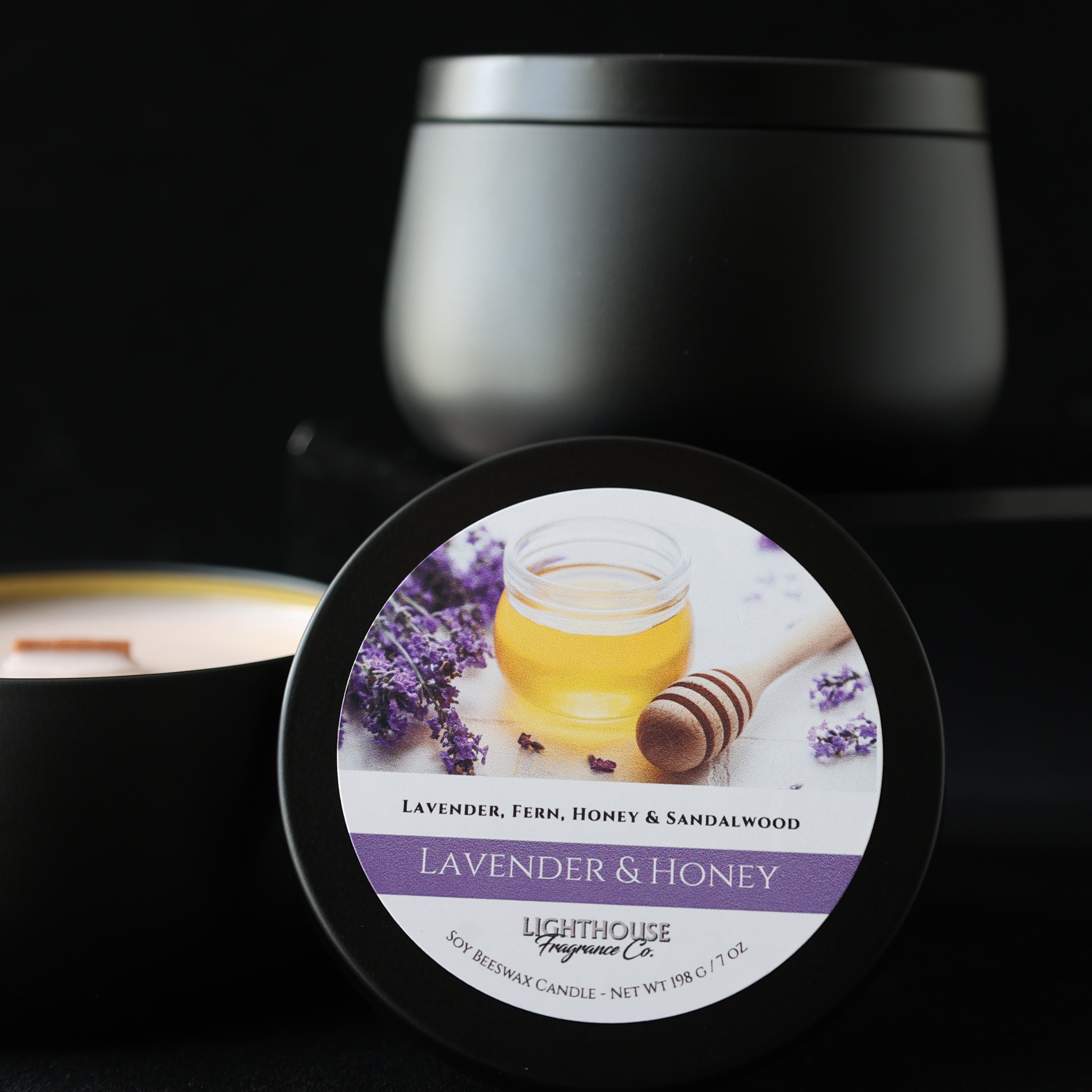 Jar of lavender and honey candle with a black lid on a dark background