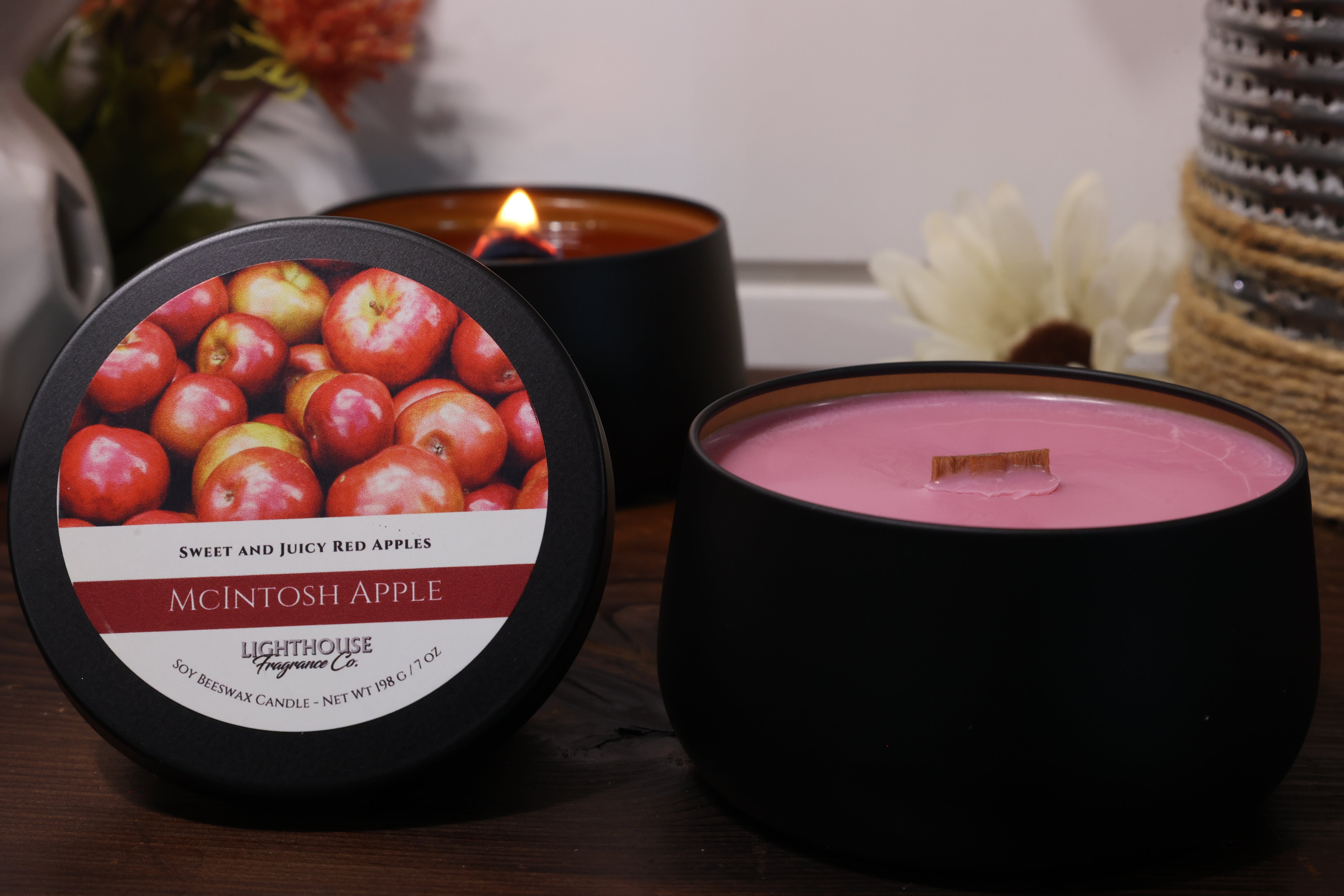 Candle with a label featuring apples and another candle in the background.