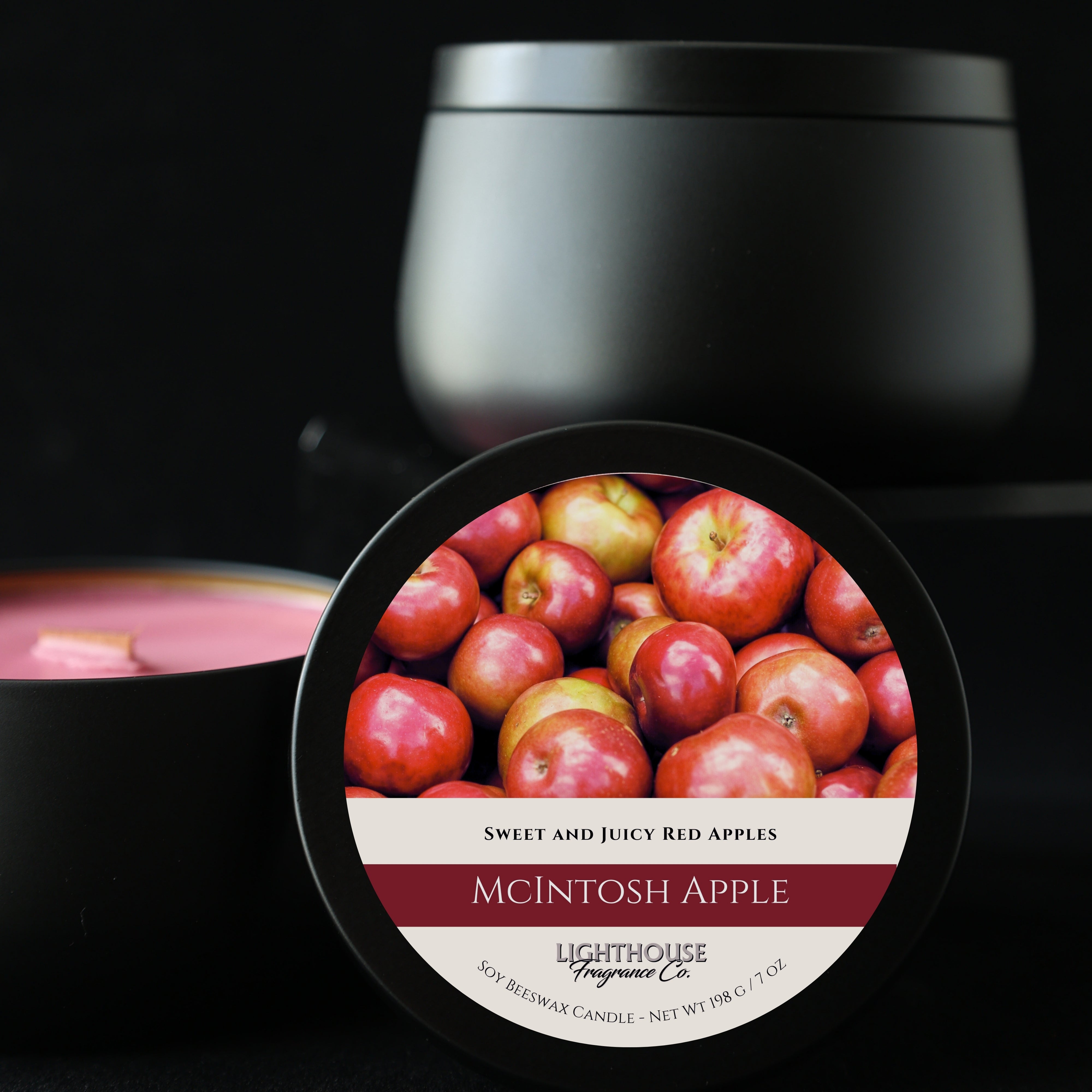 Black candle with a label featuring red apples and 'Lighthouse Fragrance Co.' branding.