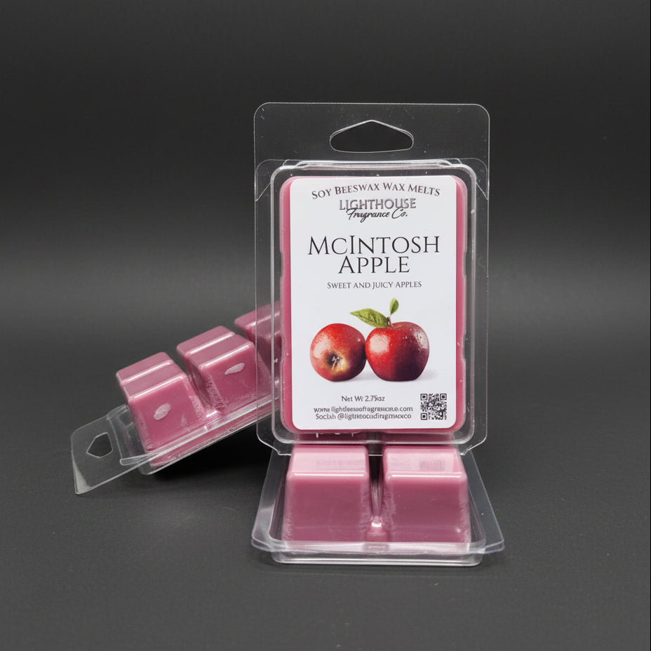 3 packages of wax melts called McIntosh Apple, with shiny red apples on the label on a dark gray surface