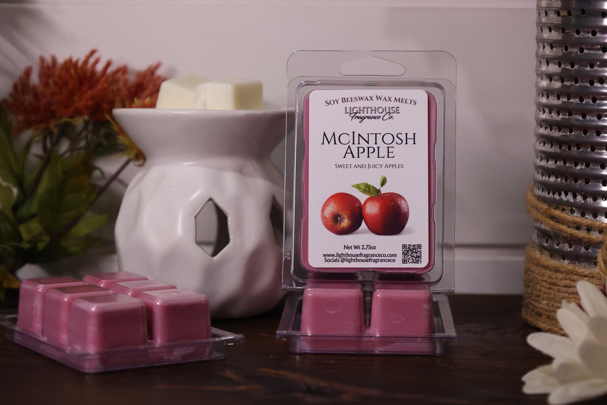 Packaged wax melts with 'McIntosh Apple' scent next to a white wax warmer on a wooden surface.