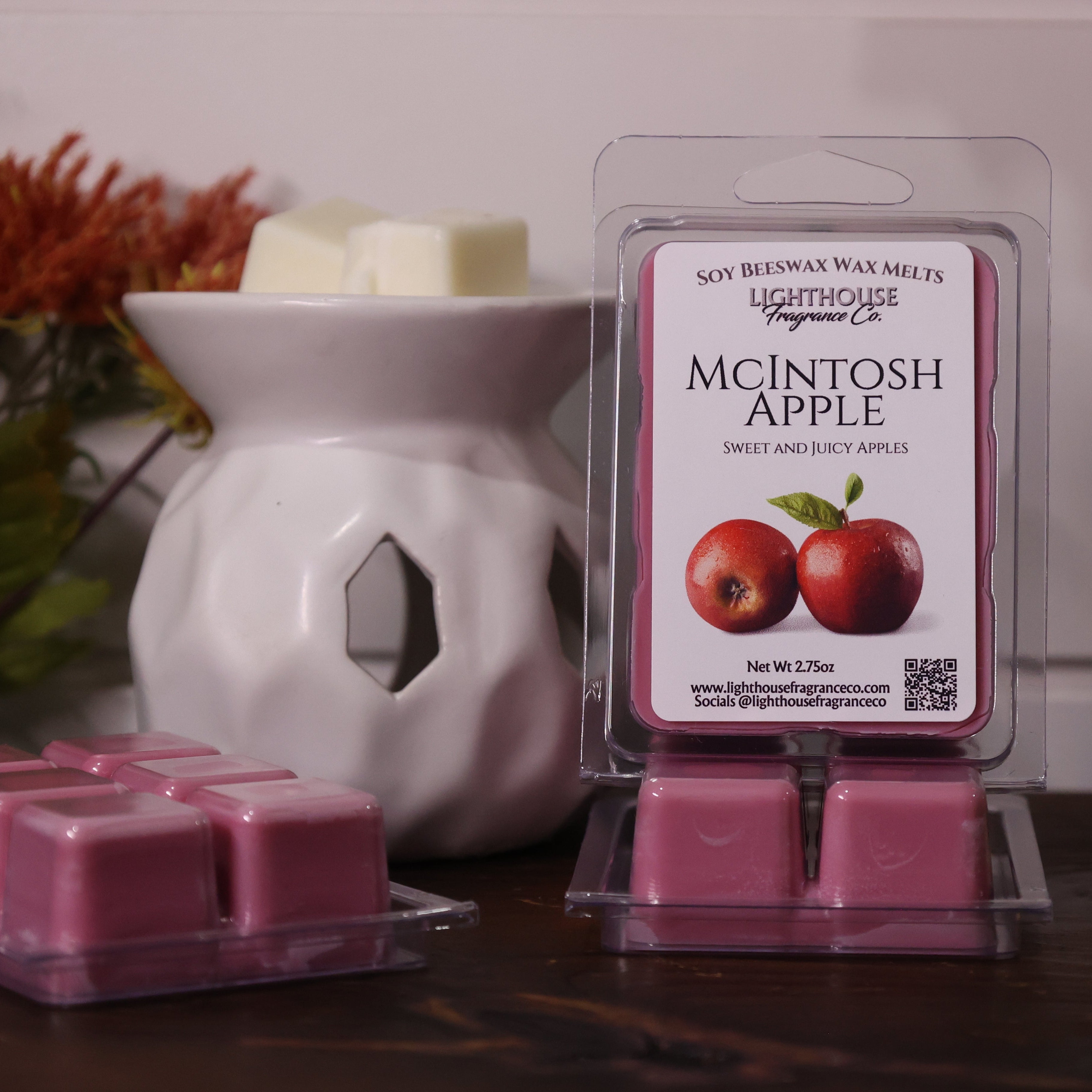 Packaged wax melts with 'McIntosh Apple' scent next to a white wax warmer on a wooden surface.