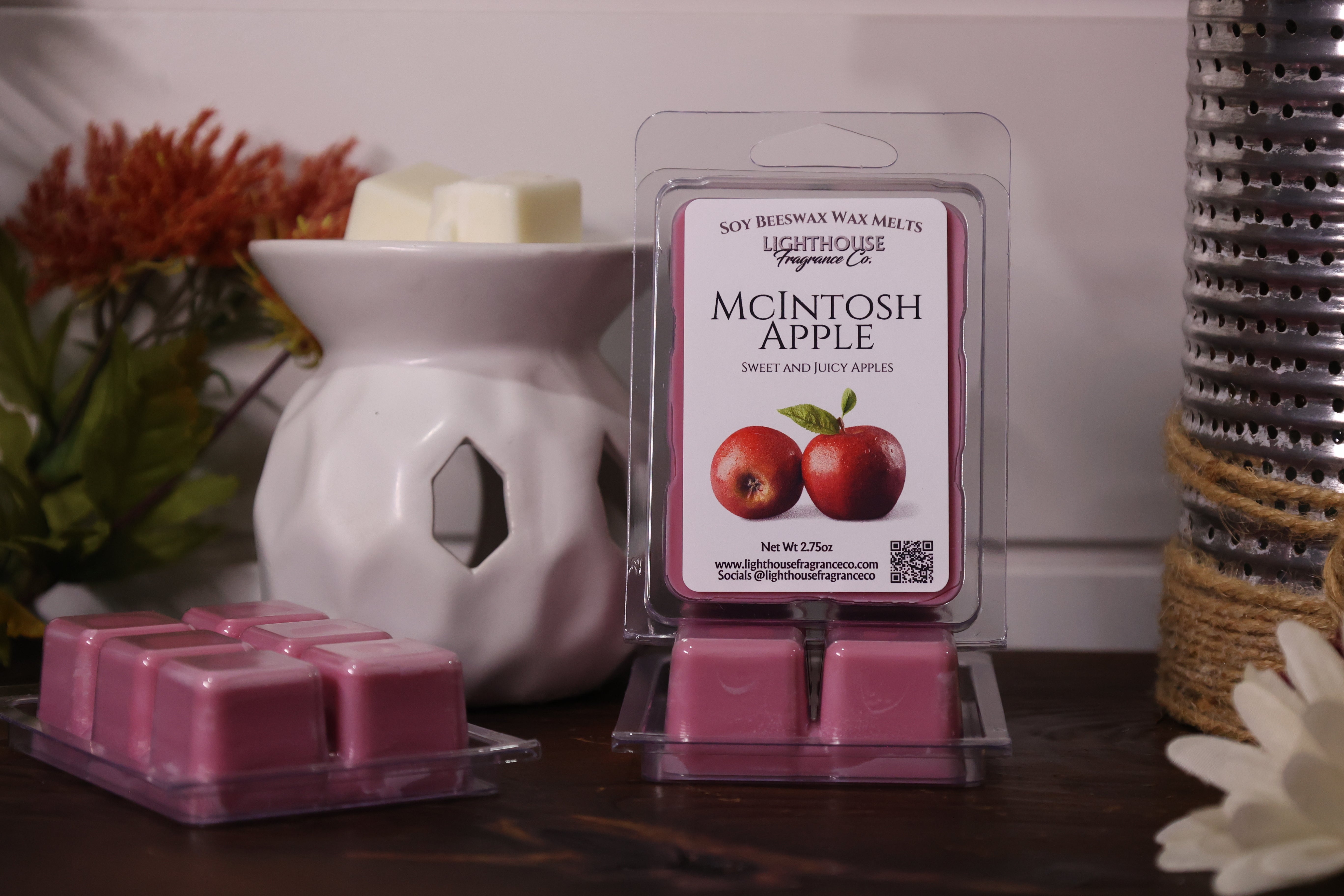 Packaged wax melts with 'McIntosh Apple' scent next to a white wax warmer on a wooden surface.