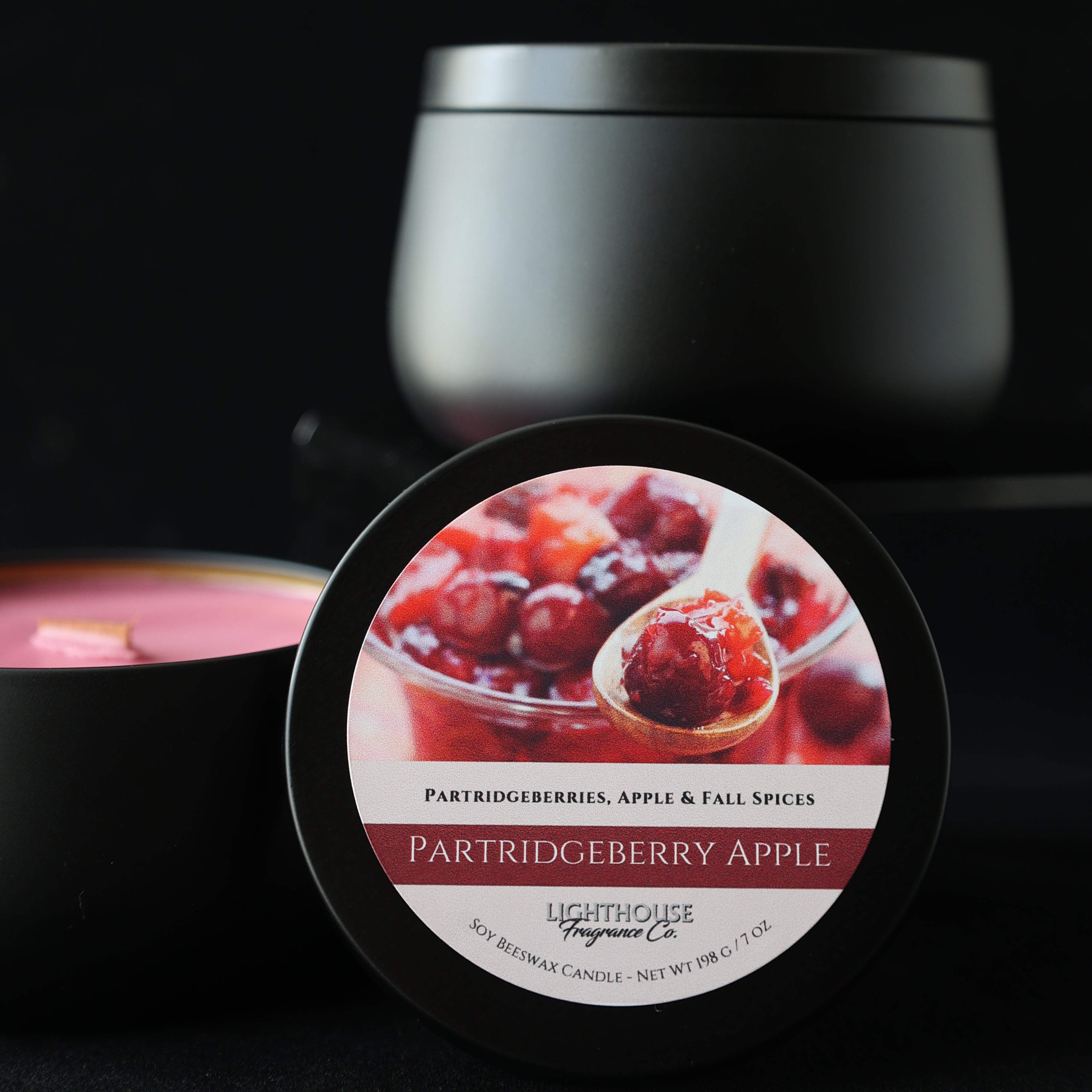 Partridgeberry Apple Candle in a black tin with a black background