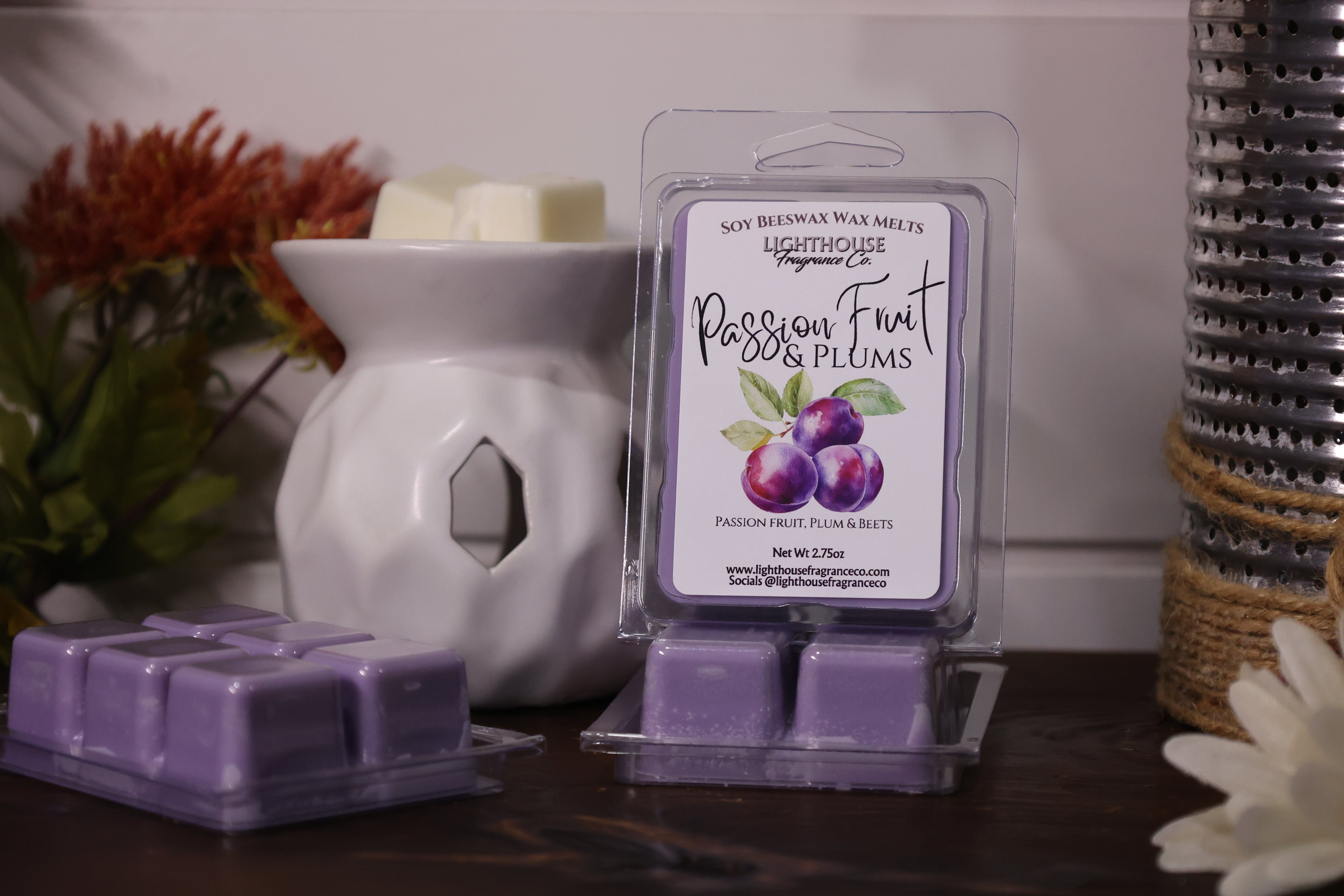 Packaged wax melts labeled 'Passion Fruit & Plums' next to a white wax warmer.