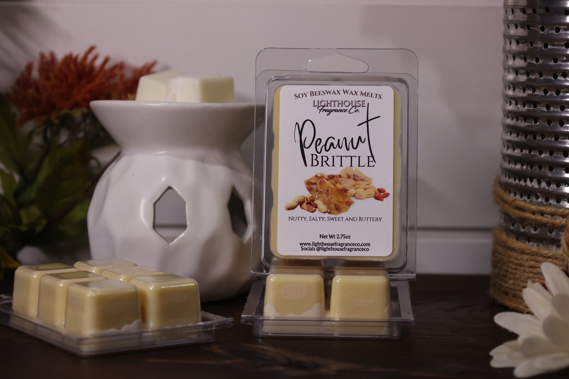 Soy wax melts with a packaging labeled 'Peanut Brittle' next to a wax warmer on a wooden surface.