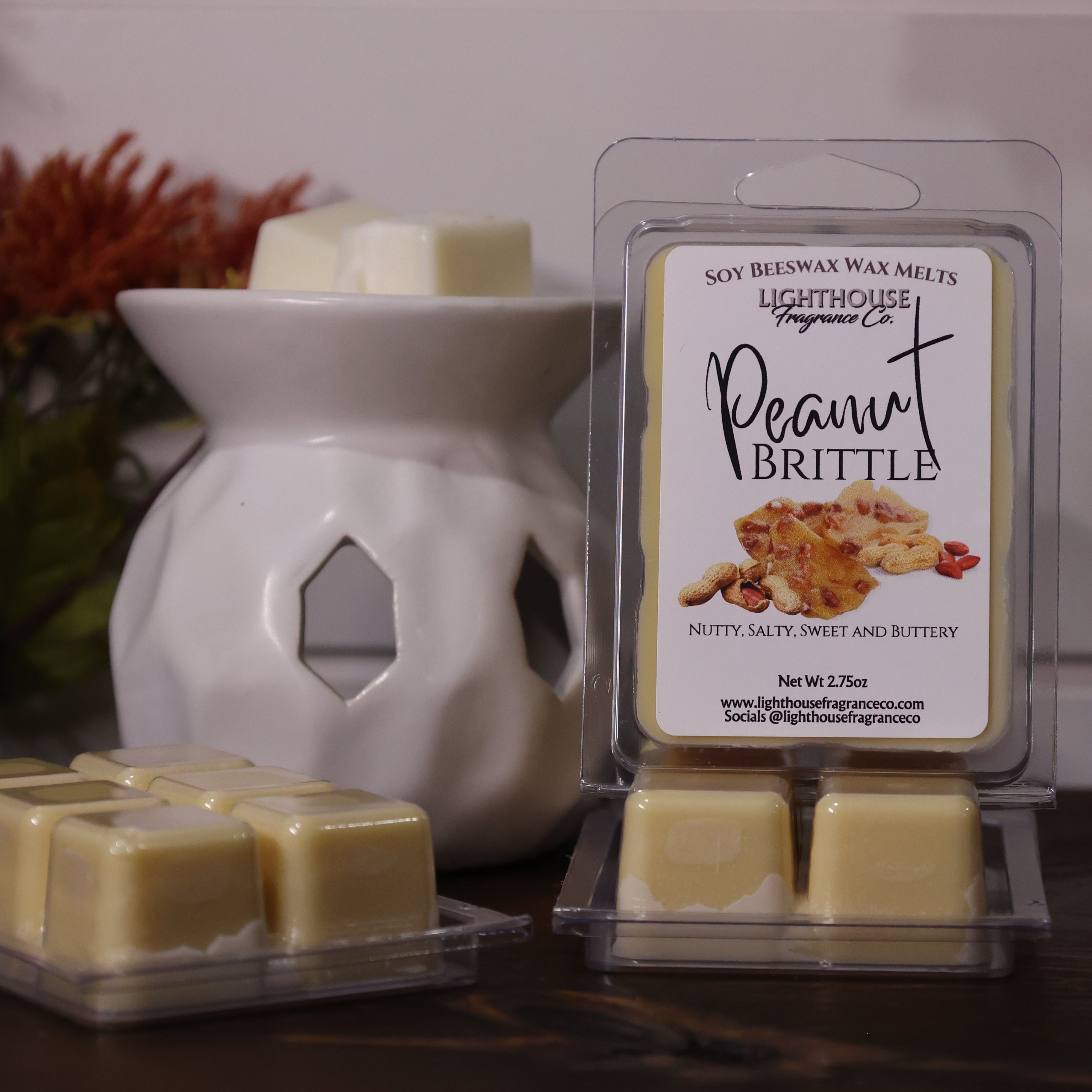 Soy wax melts with a packaging labeled 'Peanut Brittle' next to a wax warmer on a wooden surface.