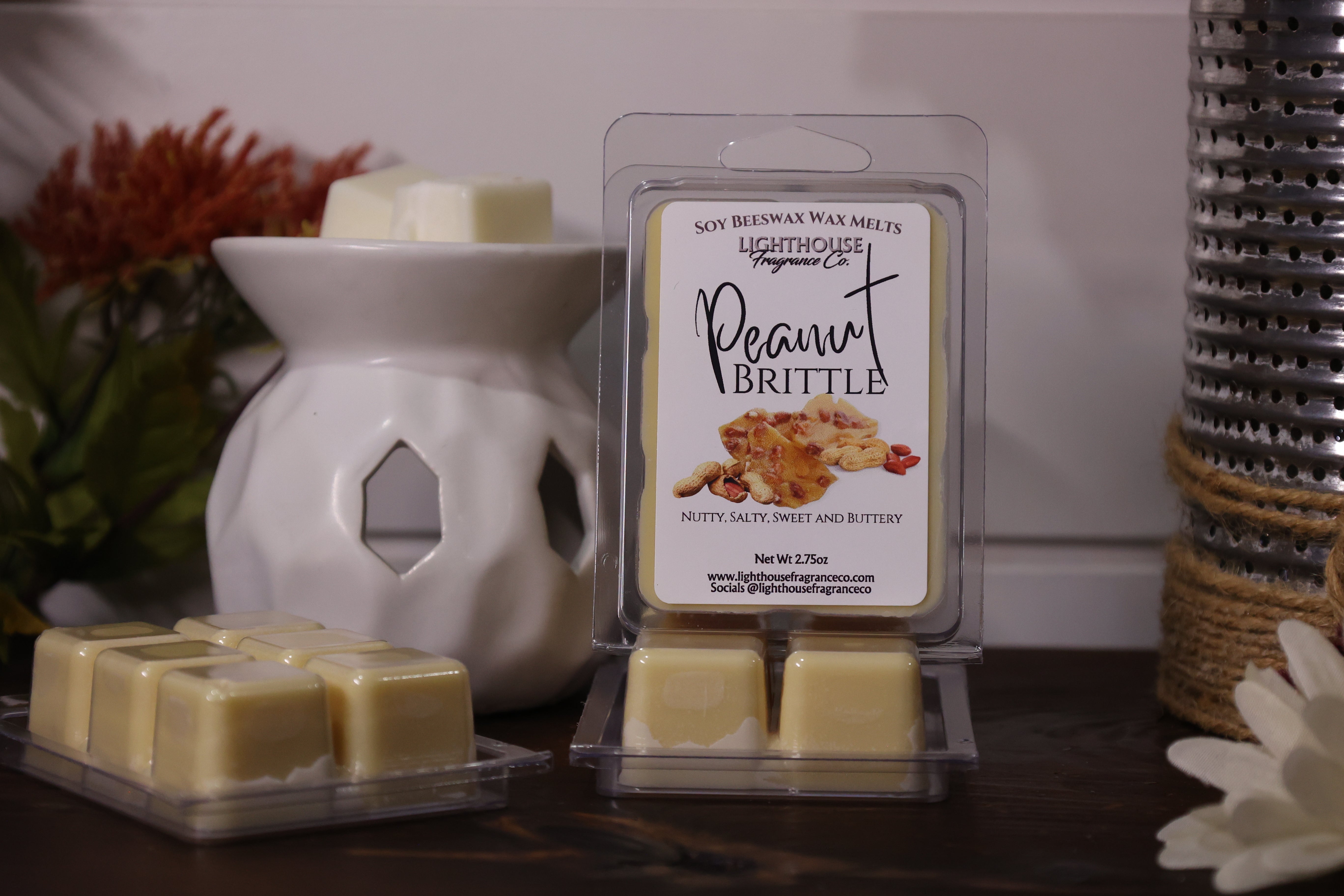 Soy wax melts with a packaging labeled 'Peanut Brittle' next to a wax warmer on a wooden surface.