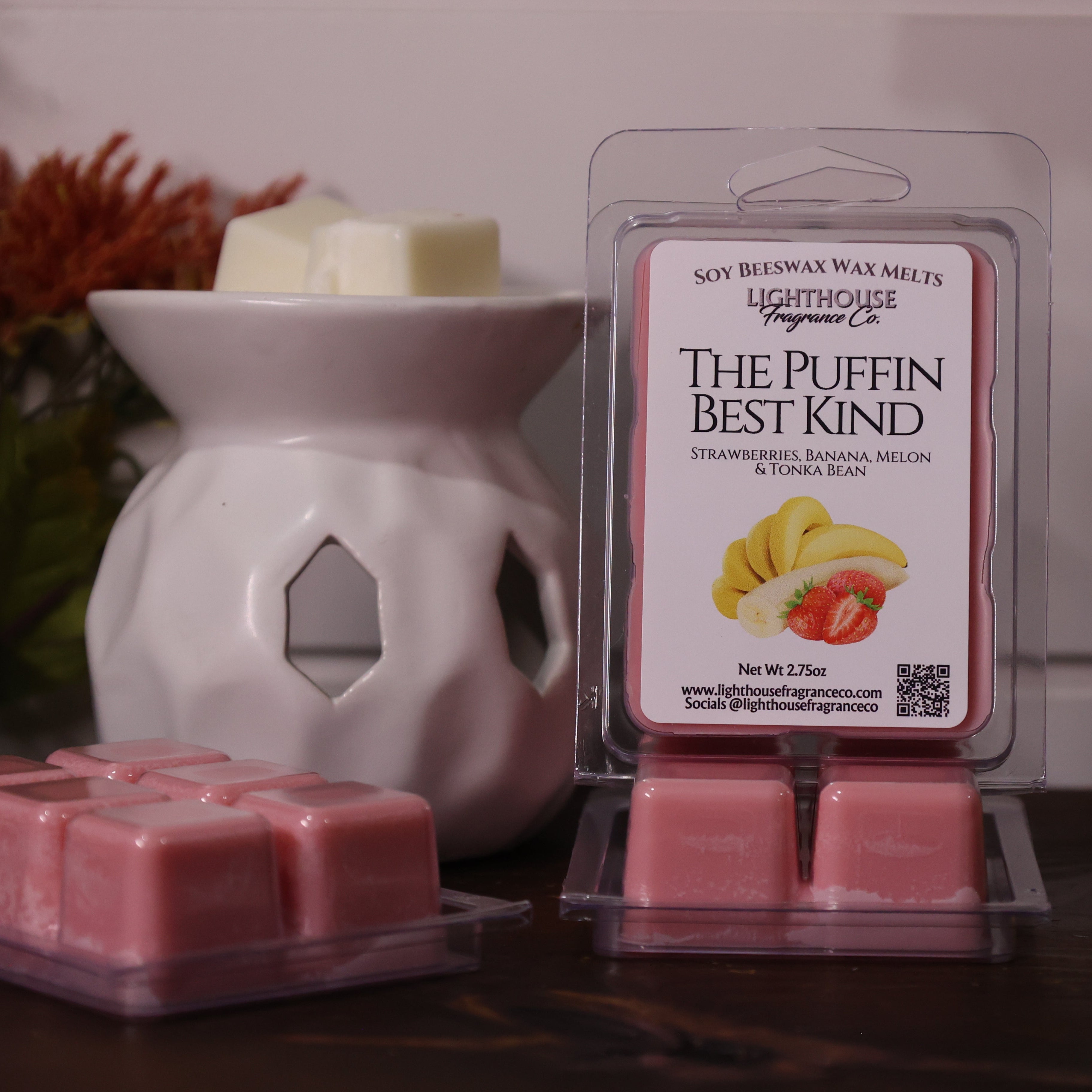 Pink wax melts in packaging with a white wax warmer on a wooden surface.