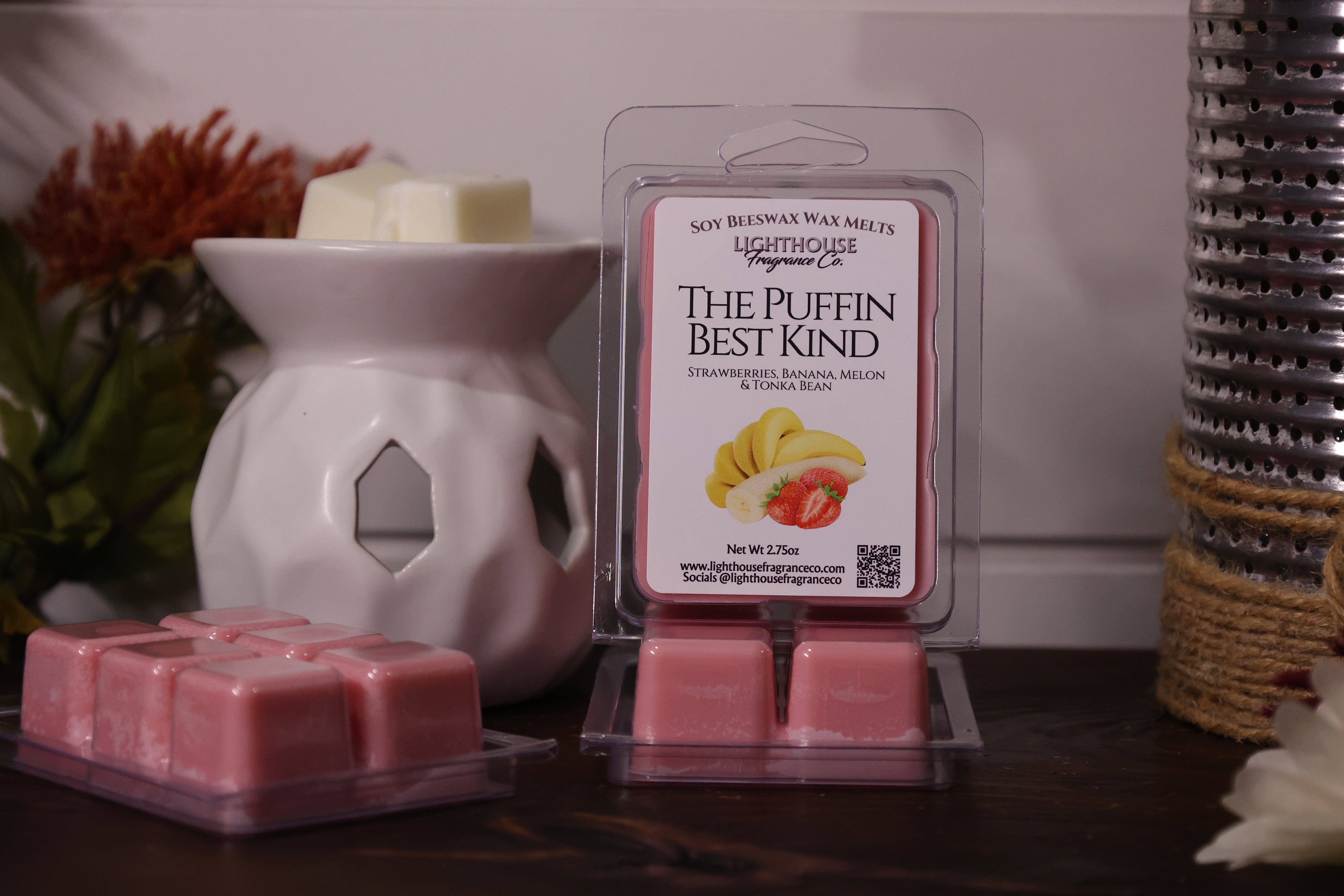 Pink wax melts in packaging with a white wax warmer on a wooden surface.