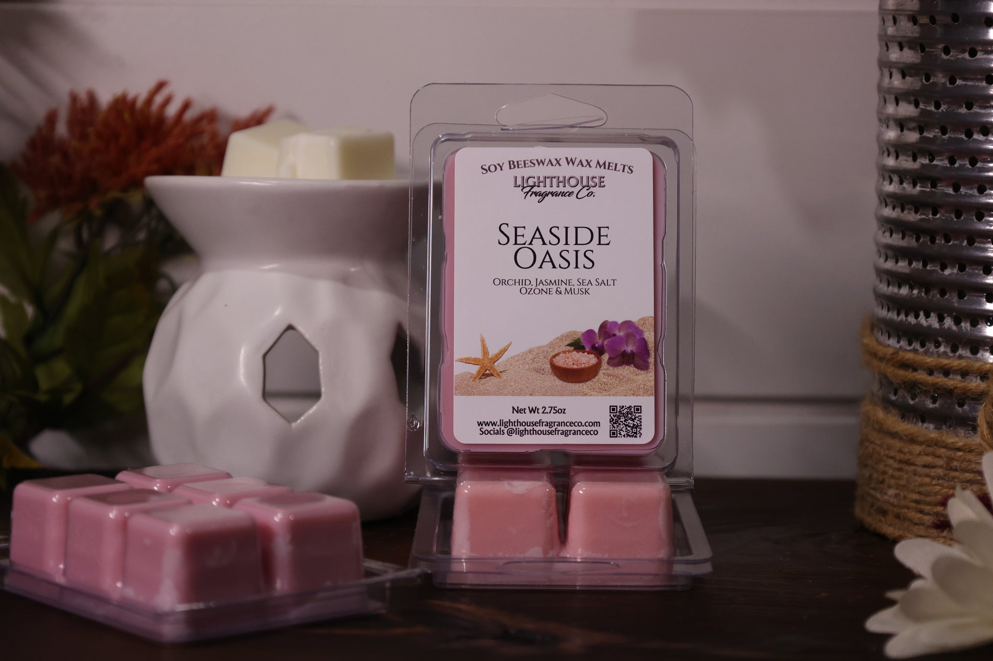 Pink wax melts in a packaging with a white wax warmer and decorative items in the background.