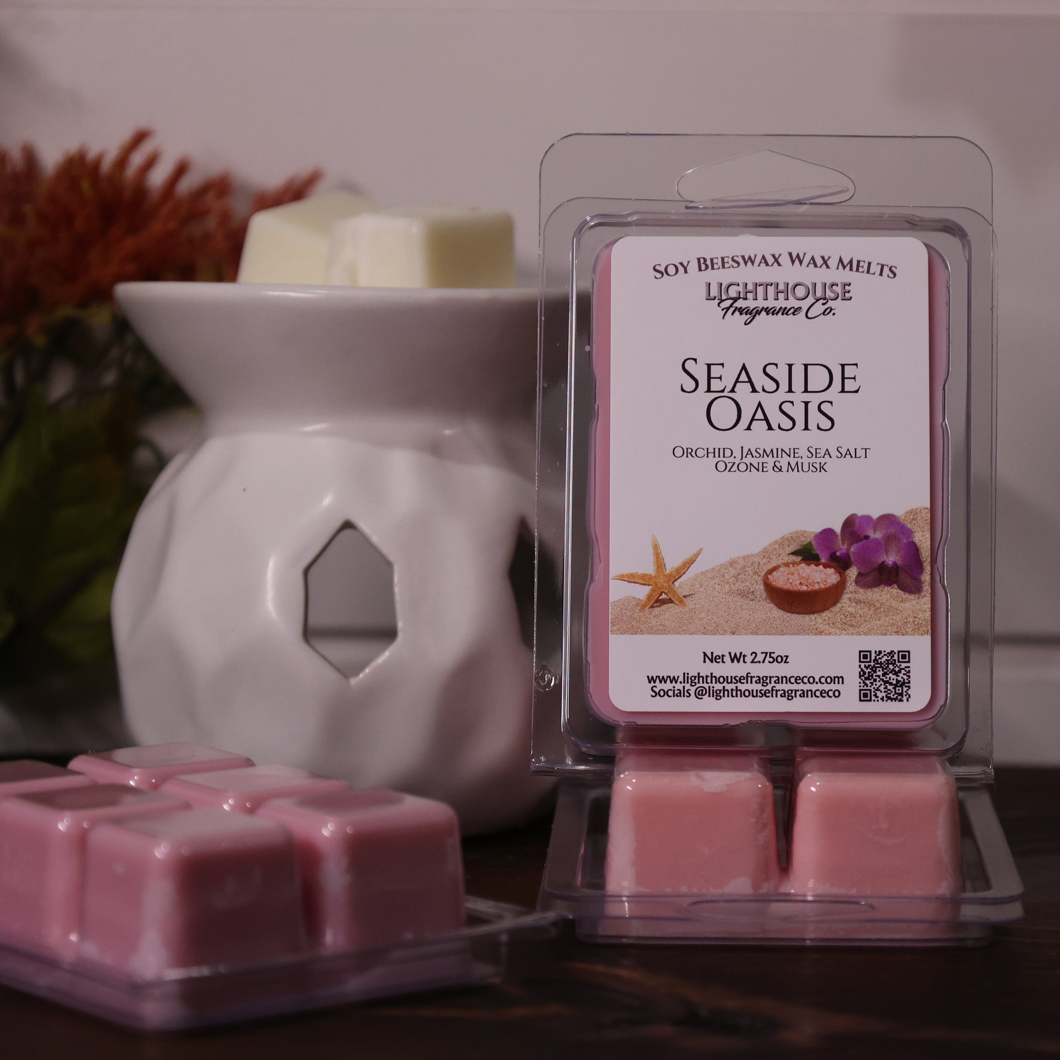 Pink wax melts in a packaging with a white wax warmer and decorative items in the background.