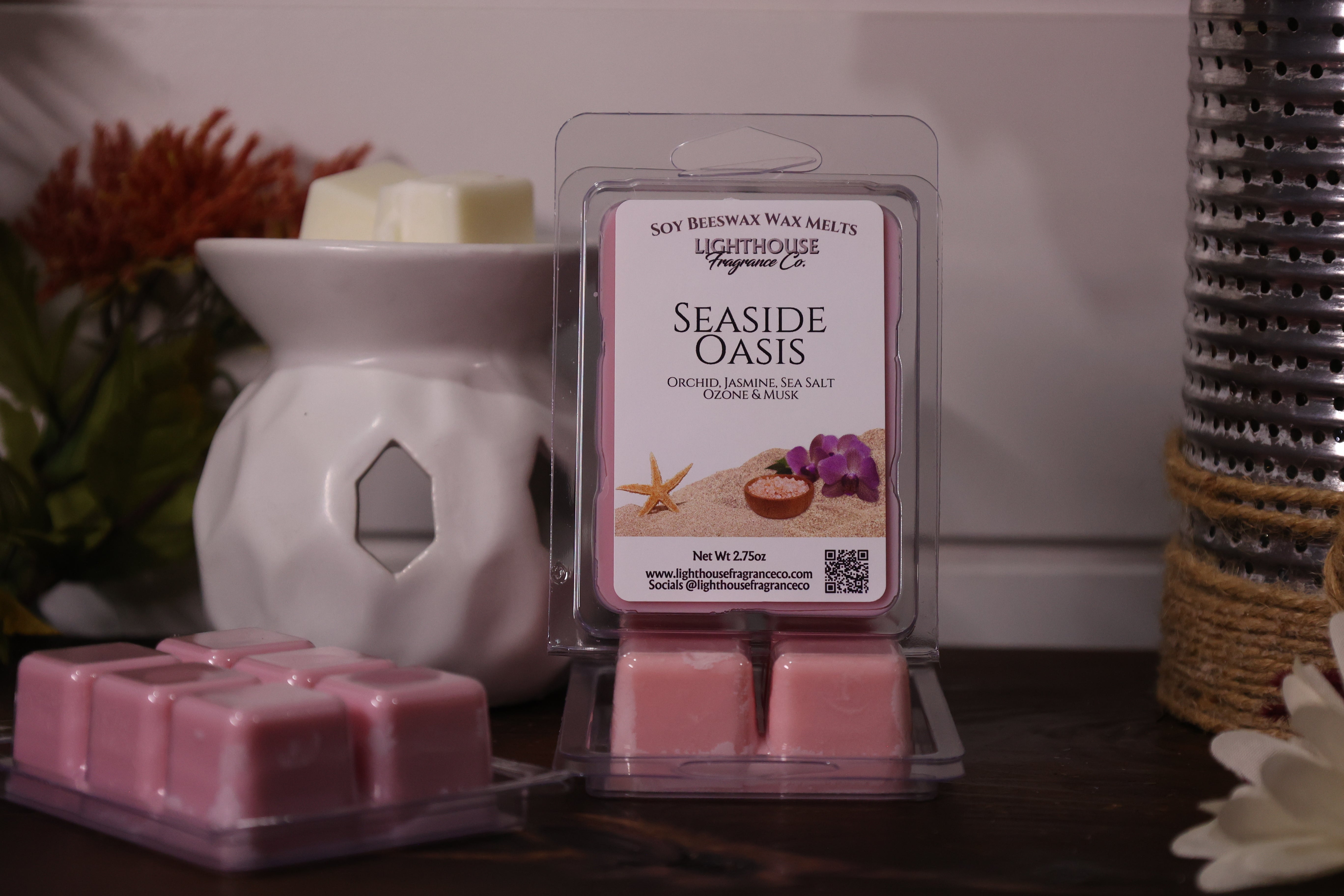 Pink wax melts in a packaging with a white wax warmer and decorative items in the background.