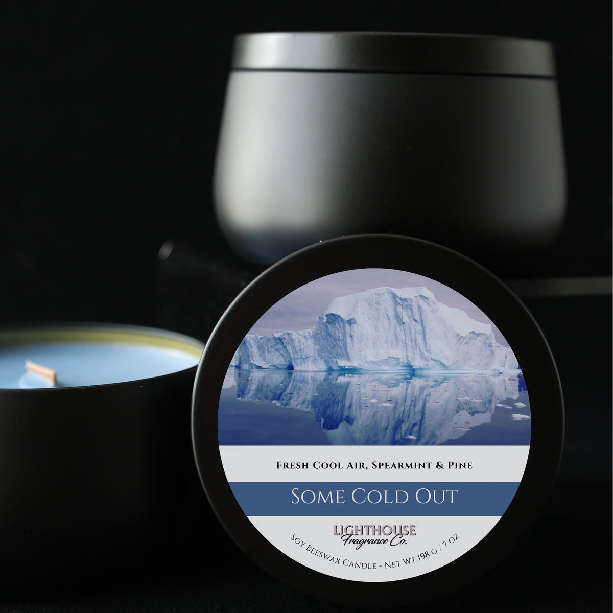 Candle with a label featuring an iceberg and 'Lighthouse Fragrances Co.' branding on a dark background.