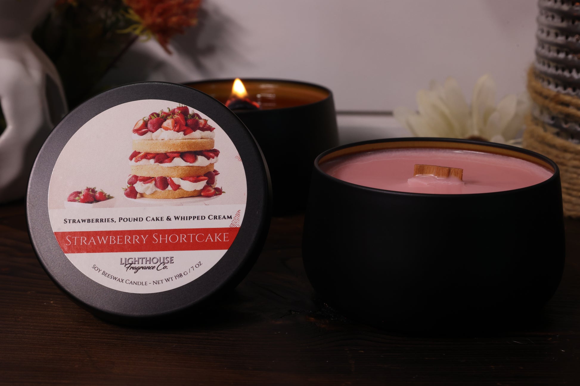 Black candle with strawberry shortcake label on a wooden surface