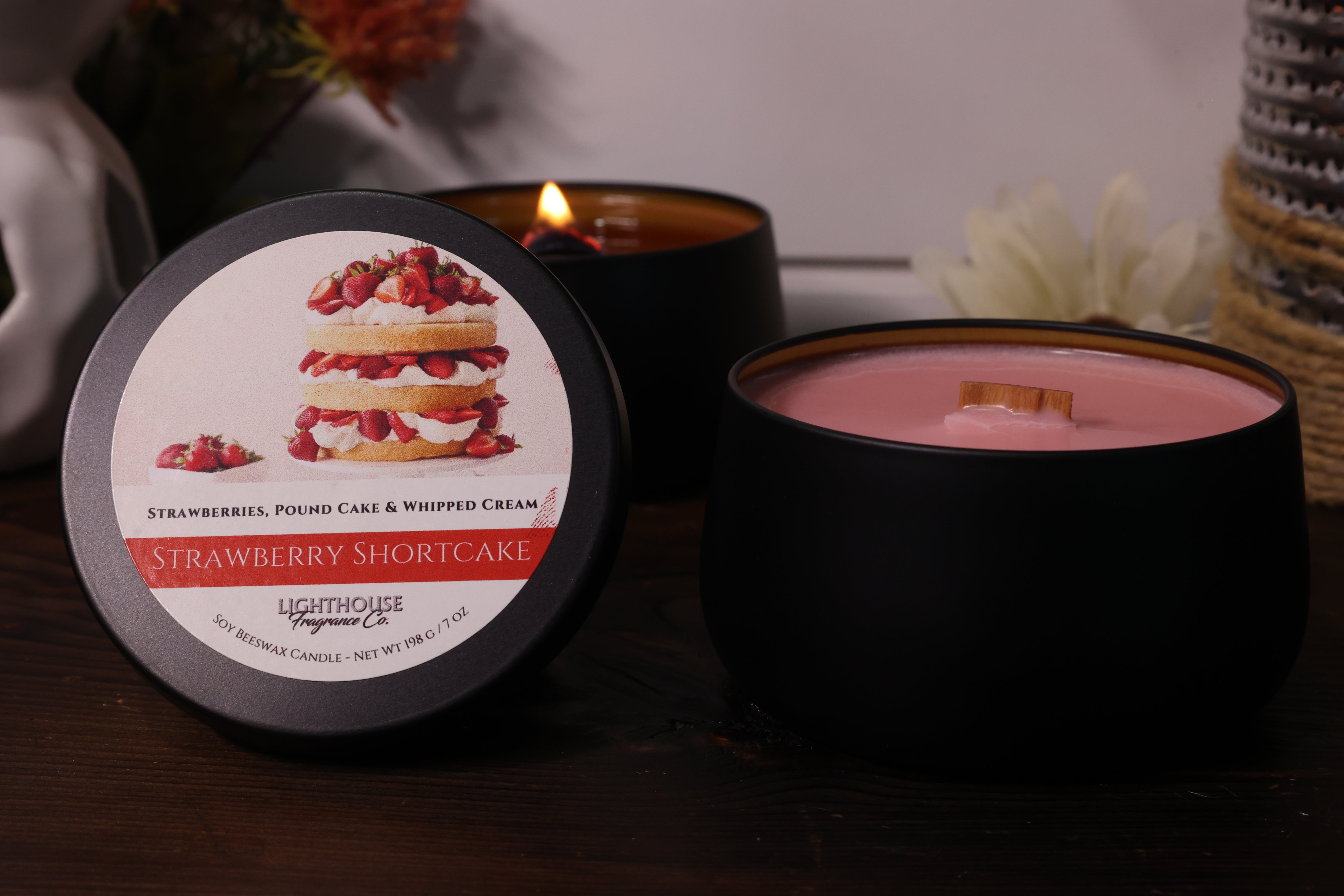 Black candle with strawberry shortcake label on a wooden surface