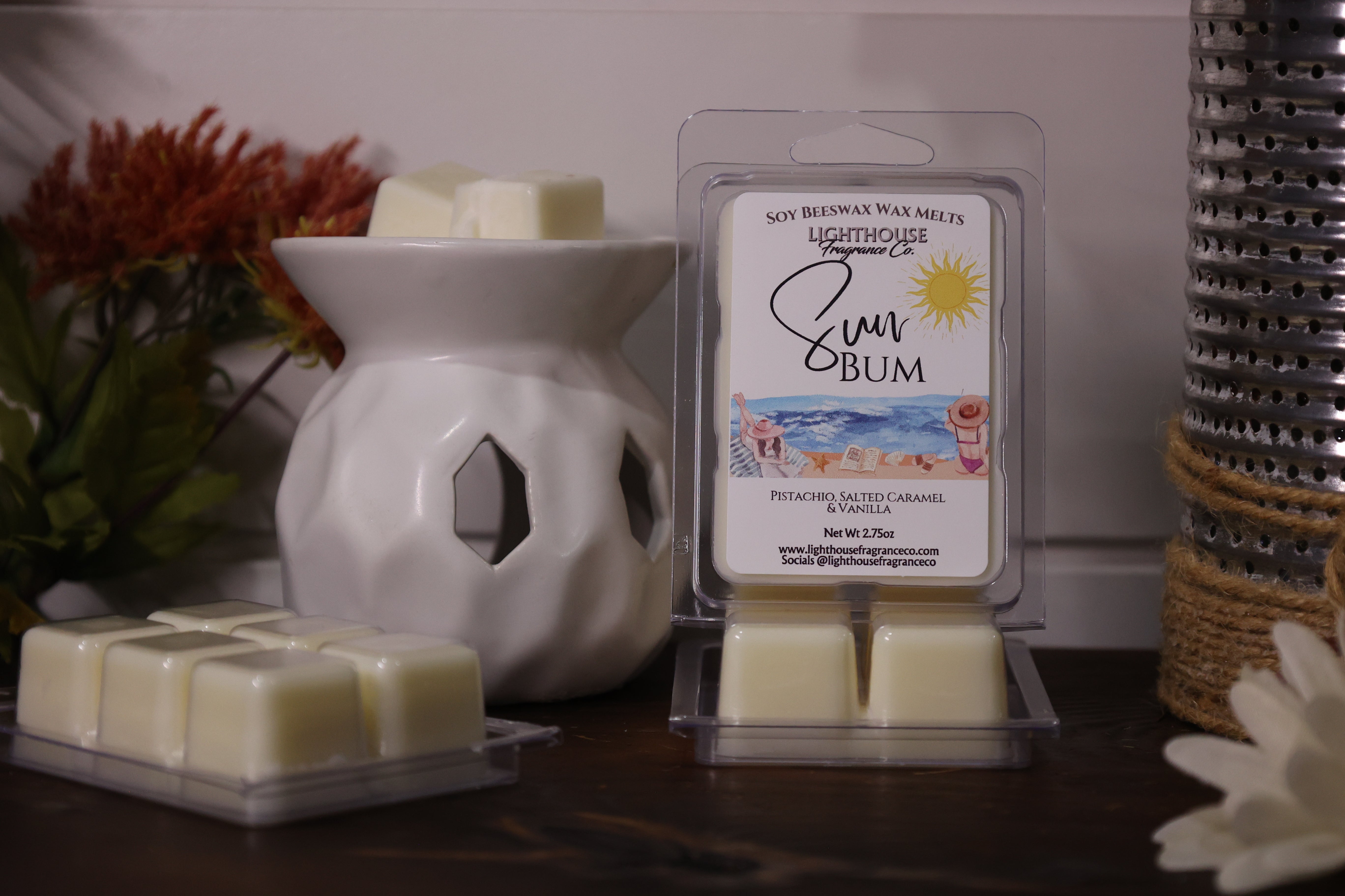 Sun Bum scent wax melts with packaging and a wax warmer on a wooden surface.