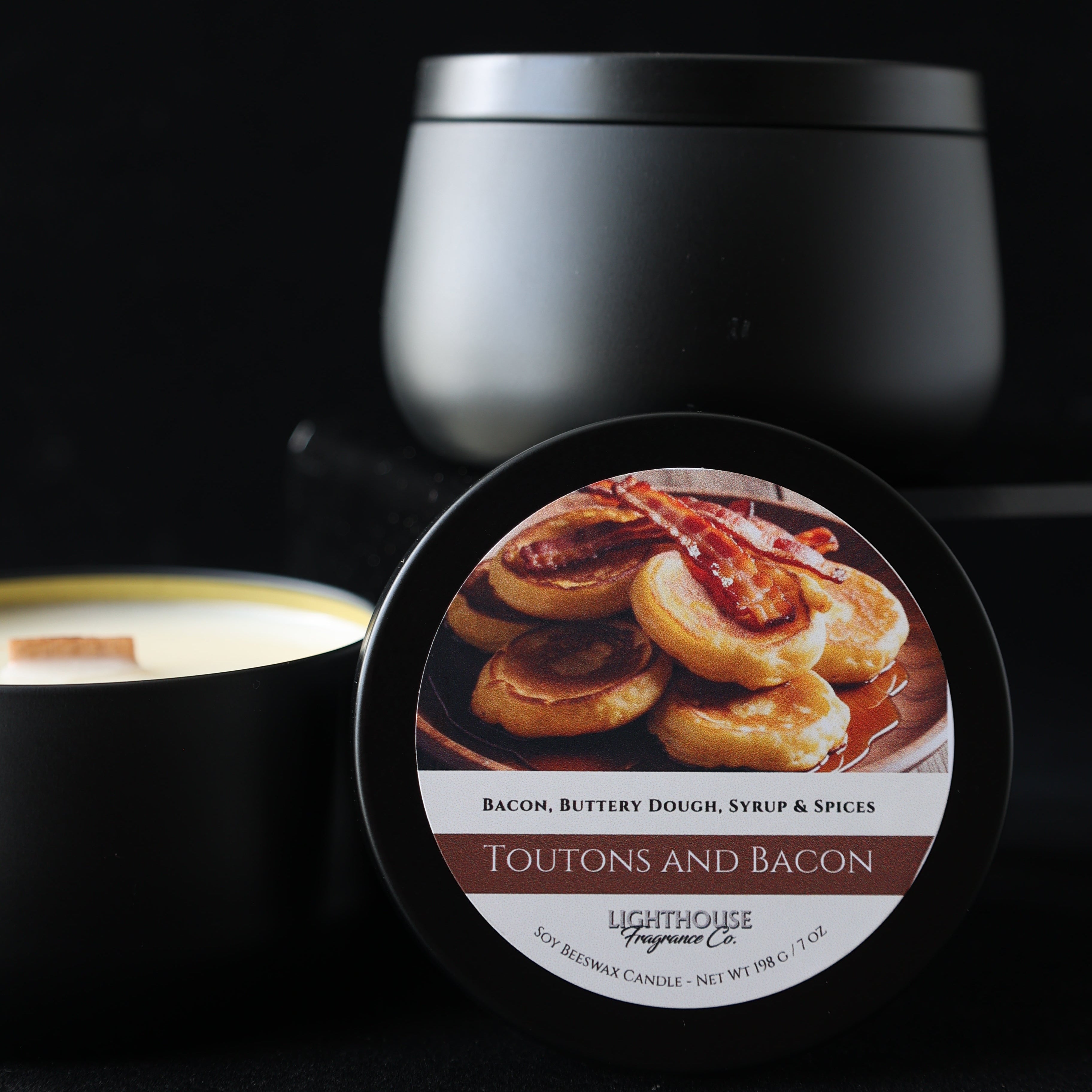 Toutons and Bacon Candle in a tin, against a black surface