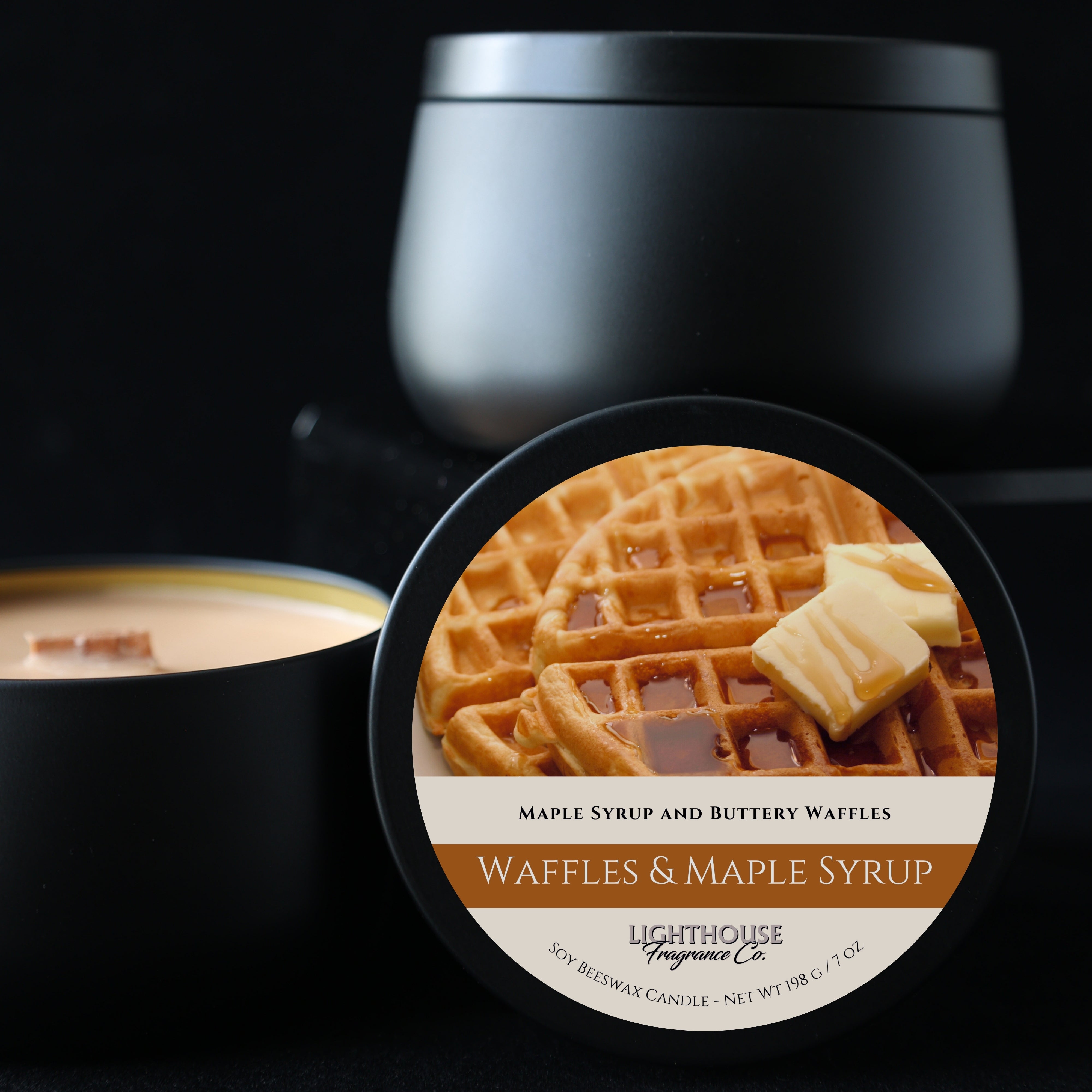 Candle with a waffles and maple syrup label in front of a black container.