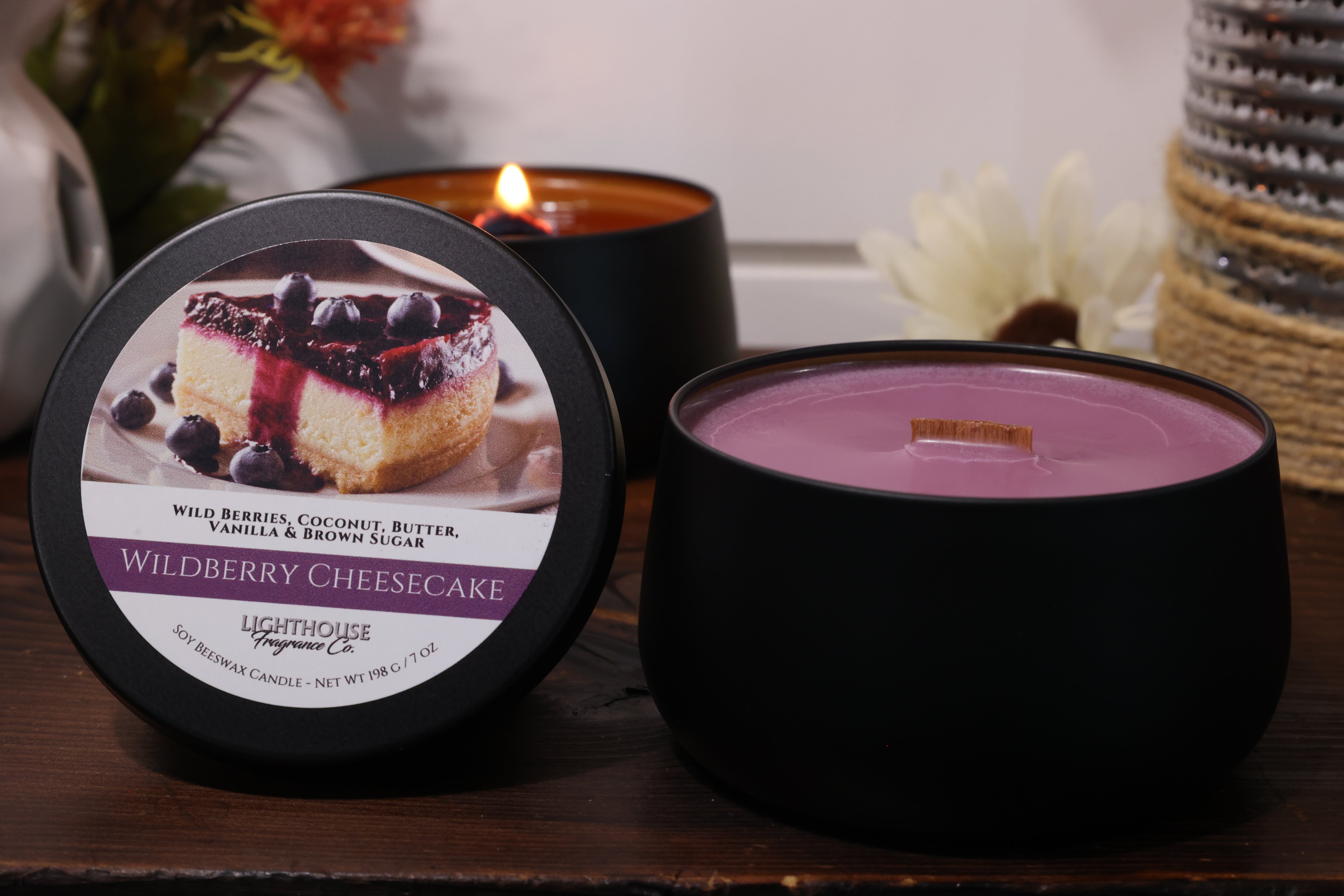 Black candle with 'Wildberry Cheesecake' label on a wooden surface