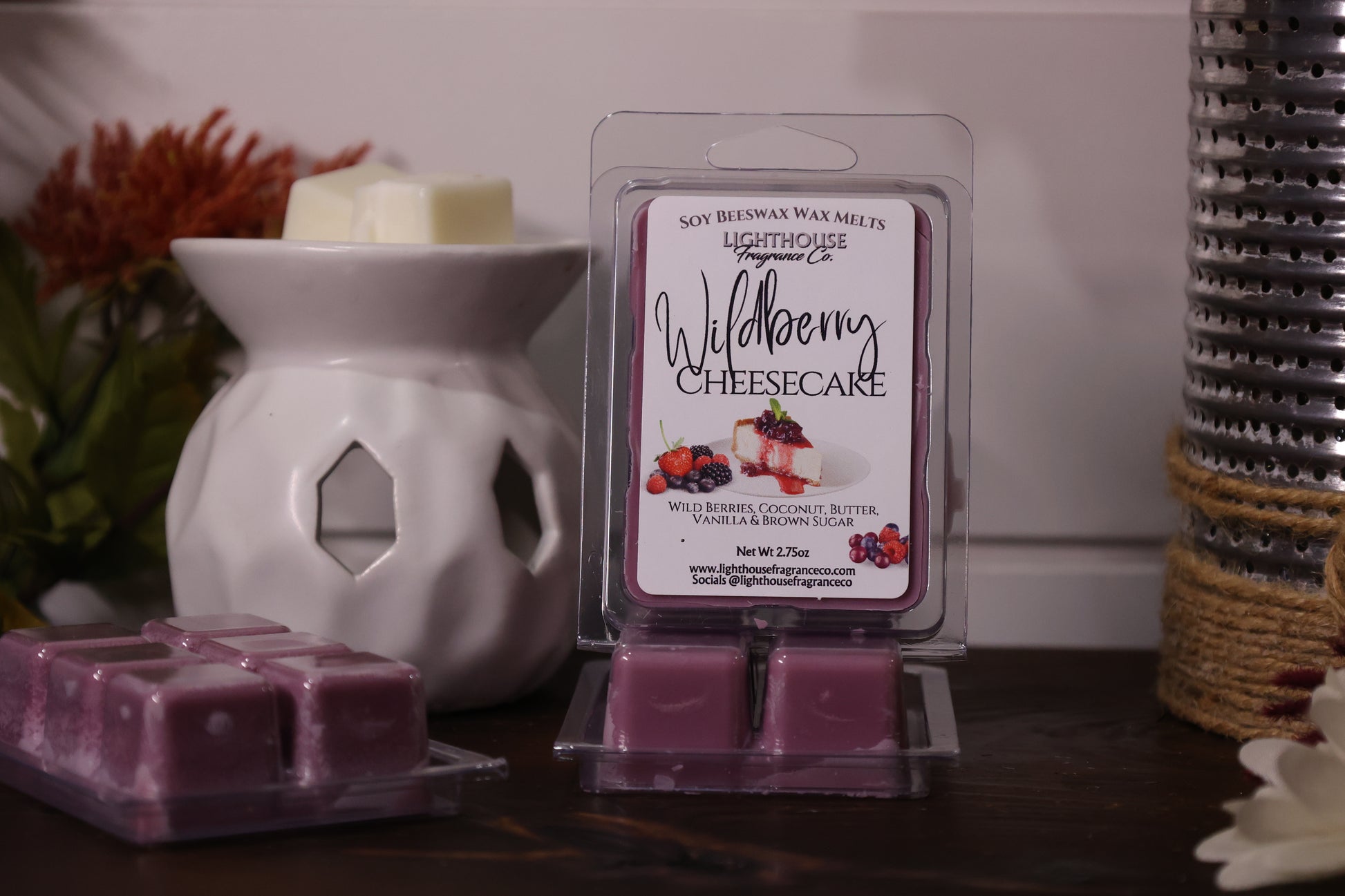 Soy wax melts packaging with 'Wildberry Cheesecake' scent next to a wax warmer on a wooden surface.