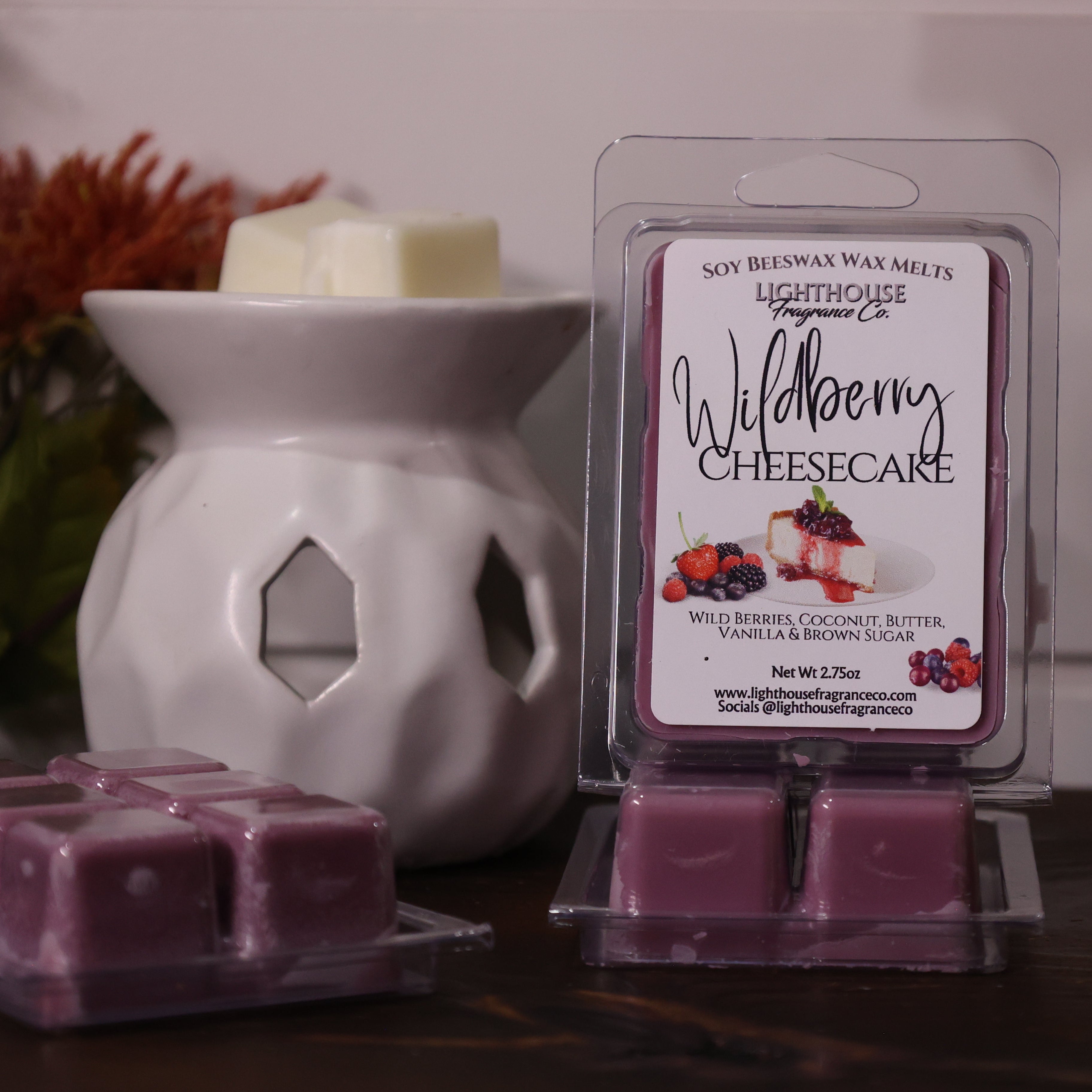 Soy wax melts packaging with 'Wildberry Cheesecake' scent next to a wax warmer on a wooden surface.