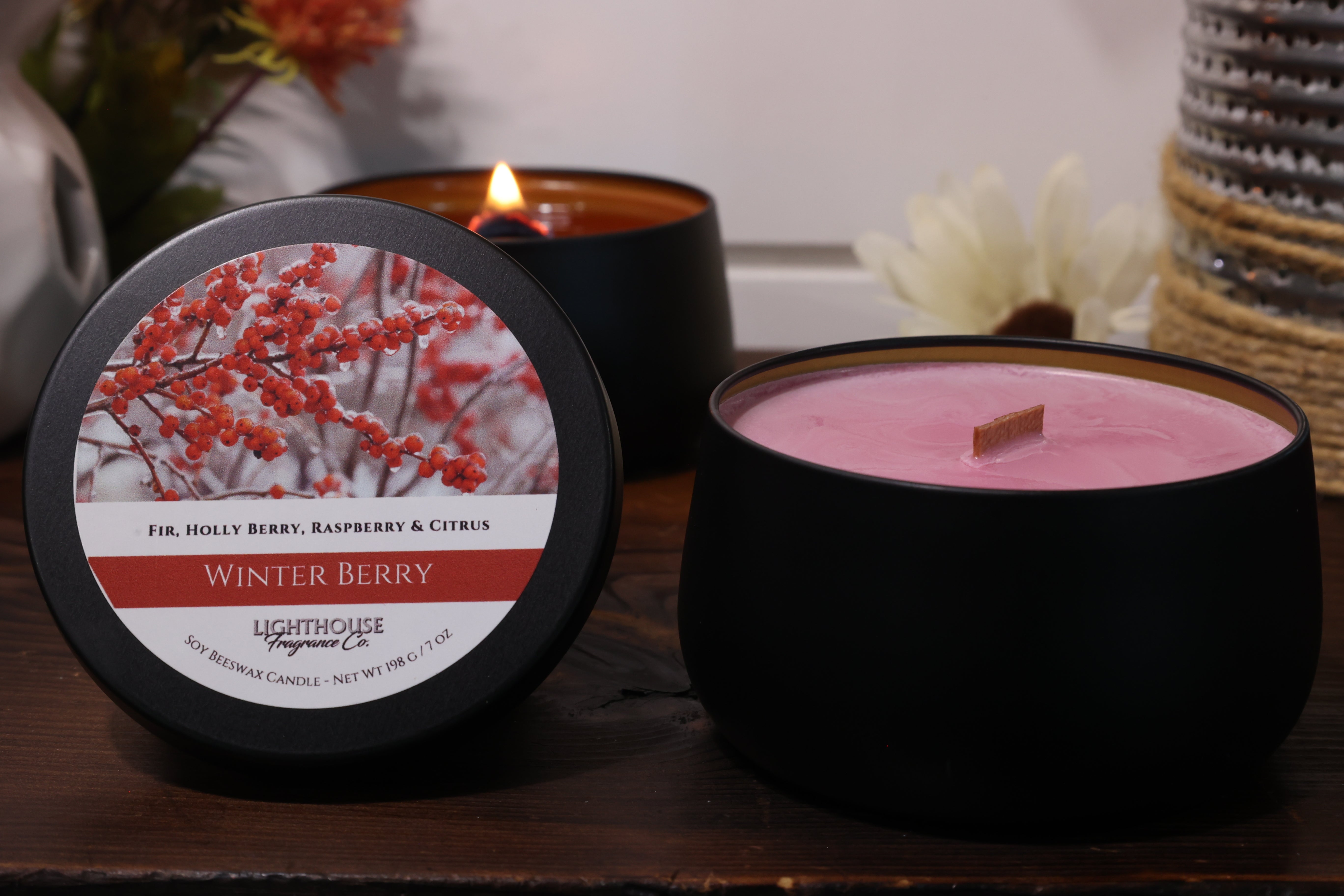 Black candle with a 'Winter Berry' label on a wooden surface
