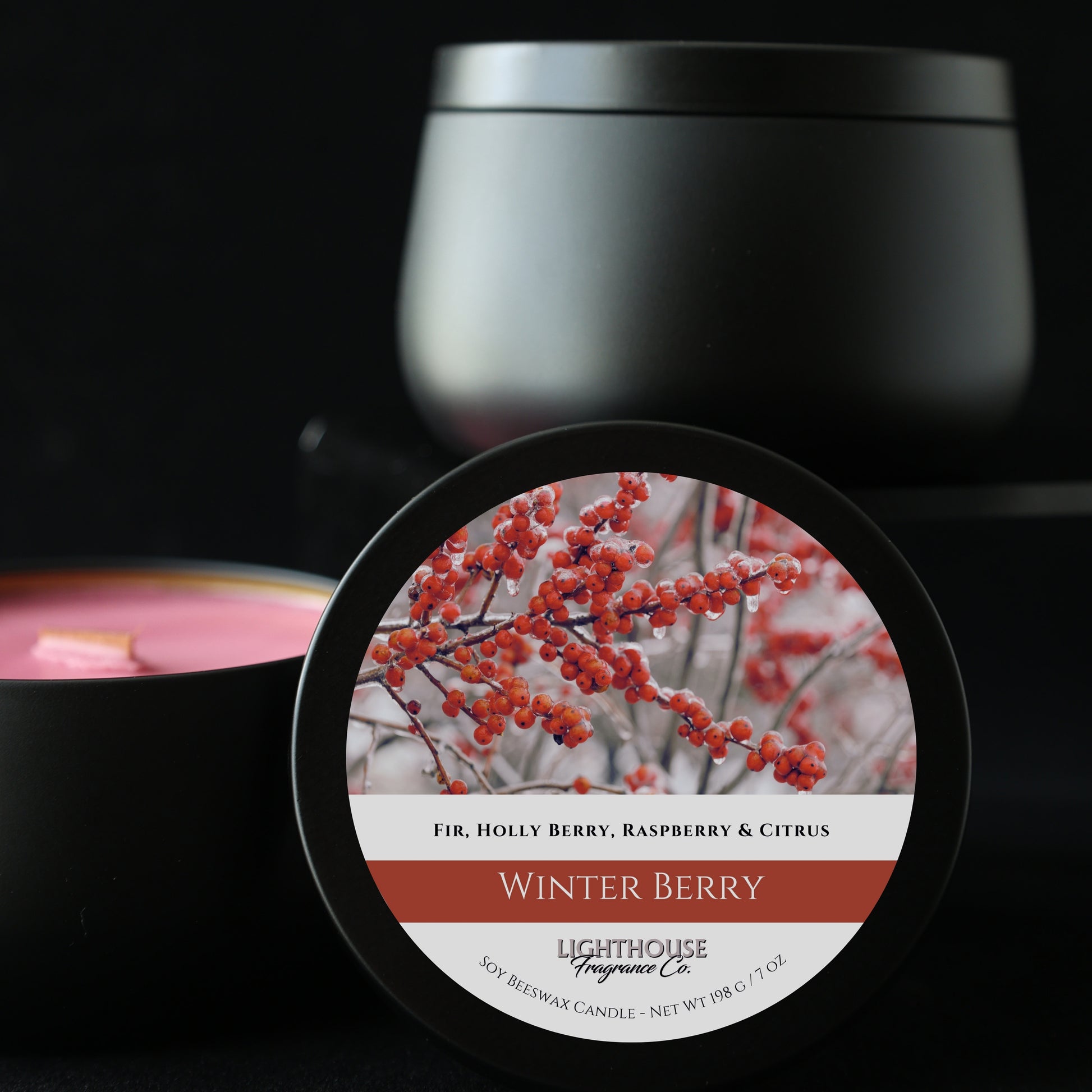 Black candle jar with a label featuring red berries on a dark background