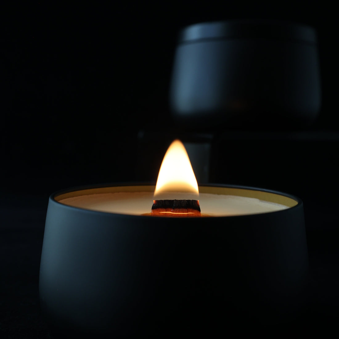 Close-up of a candle tin lit with a wooden wick